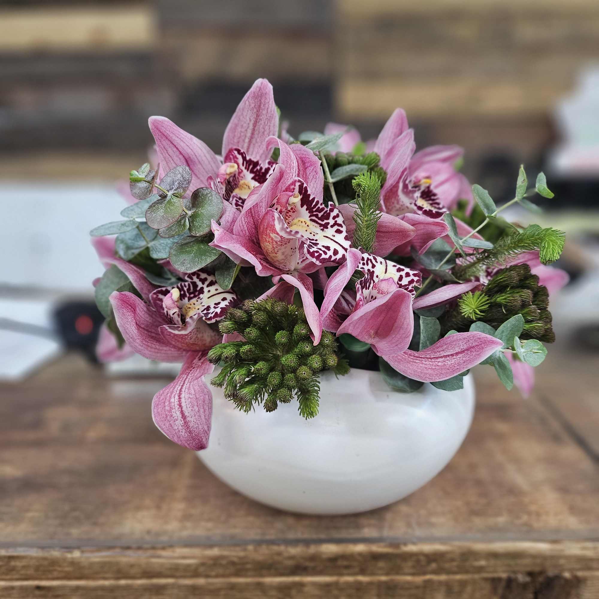 Pink orchids arranged in a white bowl vase