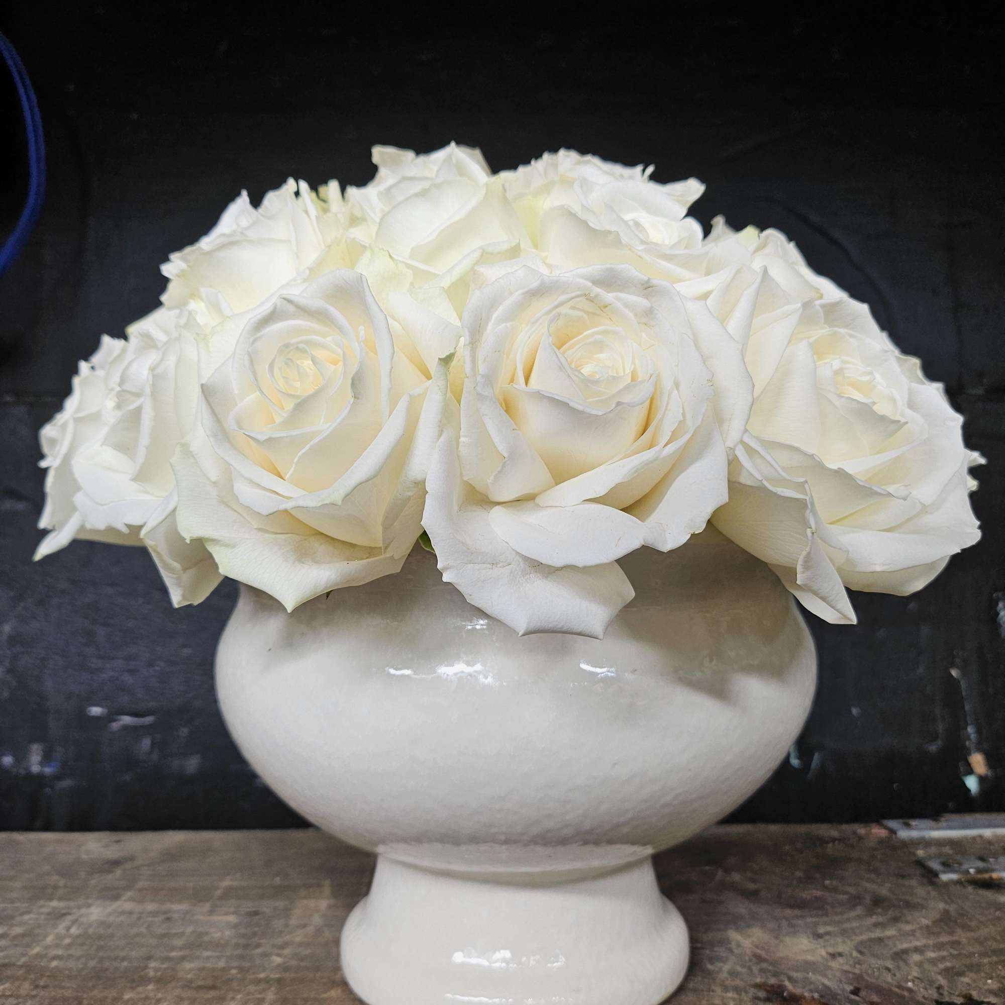 White roses arranged in a white pedestal vase