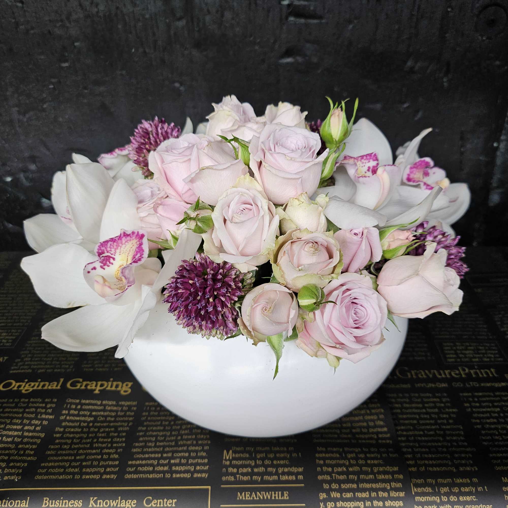 Pink roses and purple flowers arranged in a white bowl