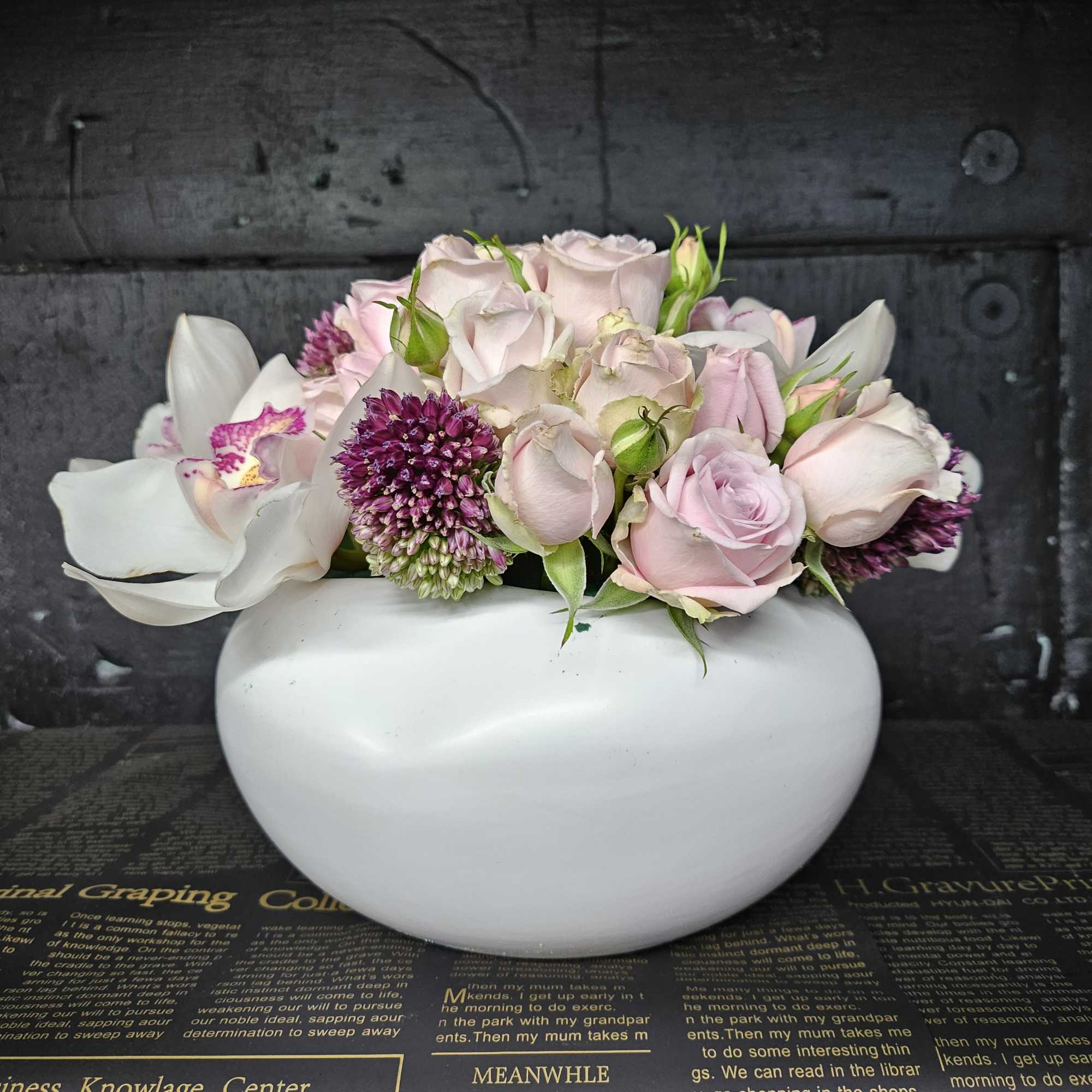 Pink roses and white orchids arranged in a white vase