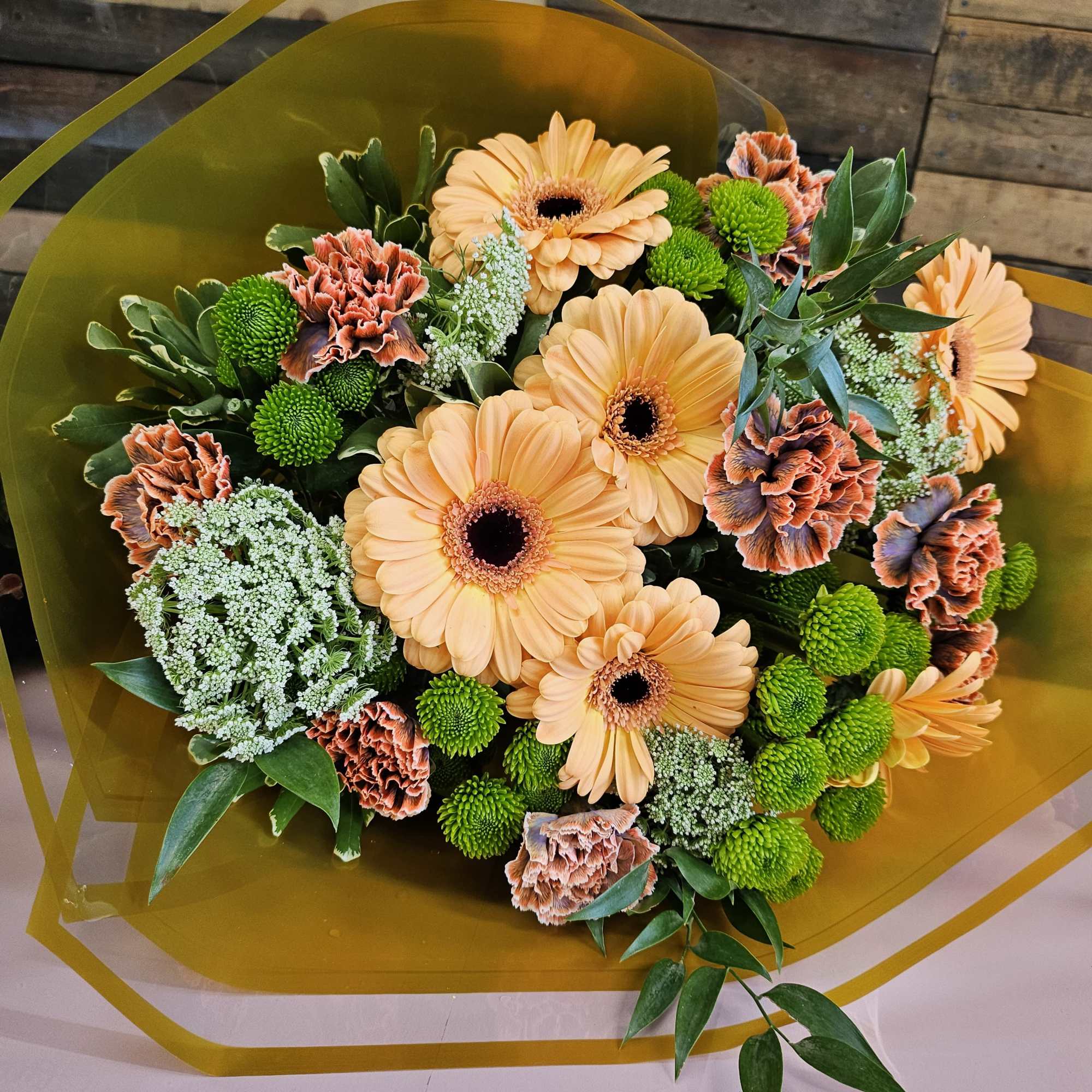 Bouquet of peach gerbera daisies and green button mums with orange carnations