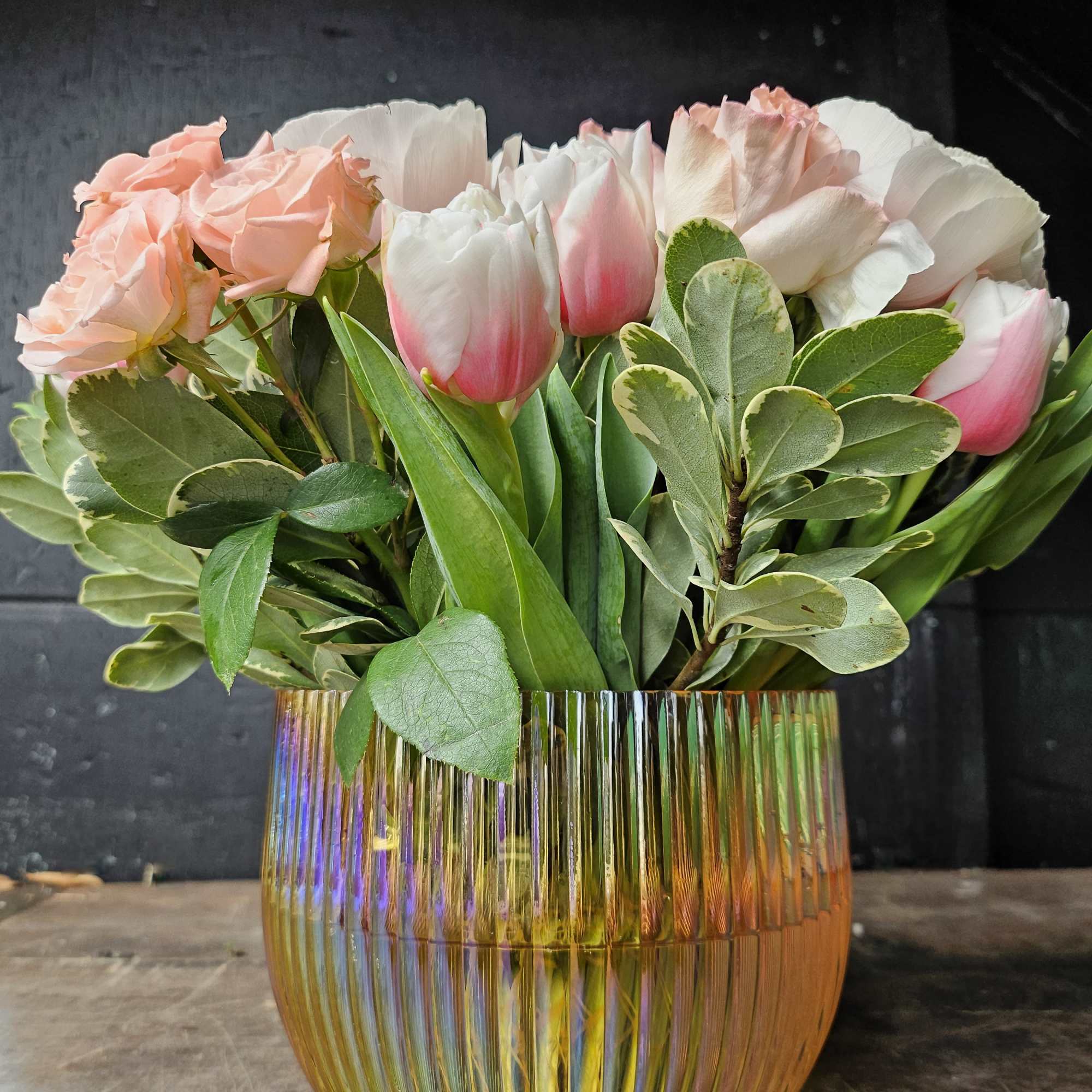Pink roses and white tulips in a ribbed glass vase