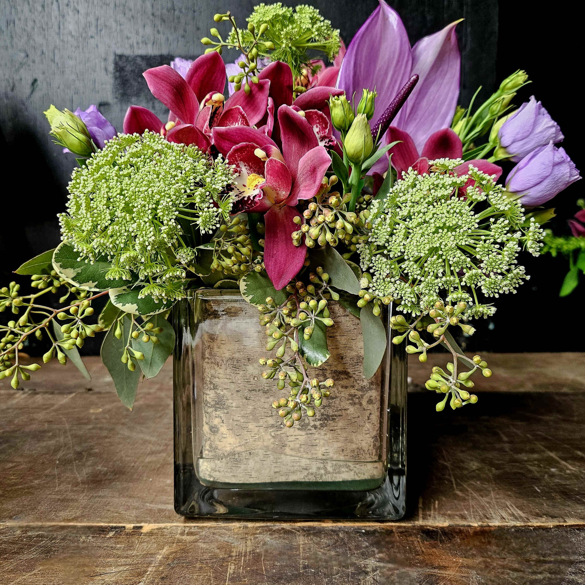 Pink and purple floral arrangement in a square glass vase