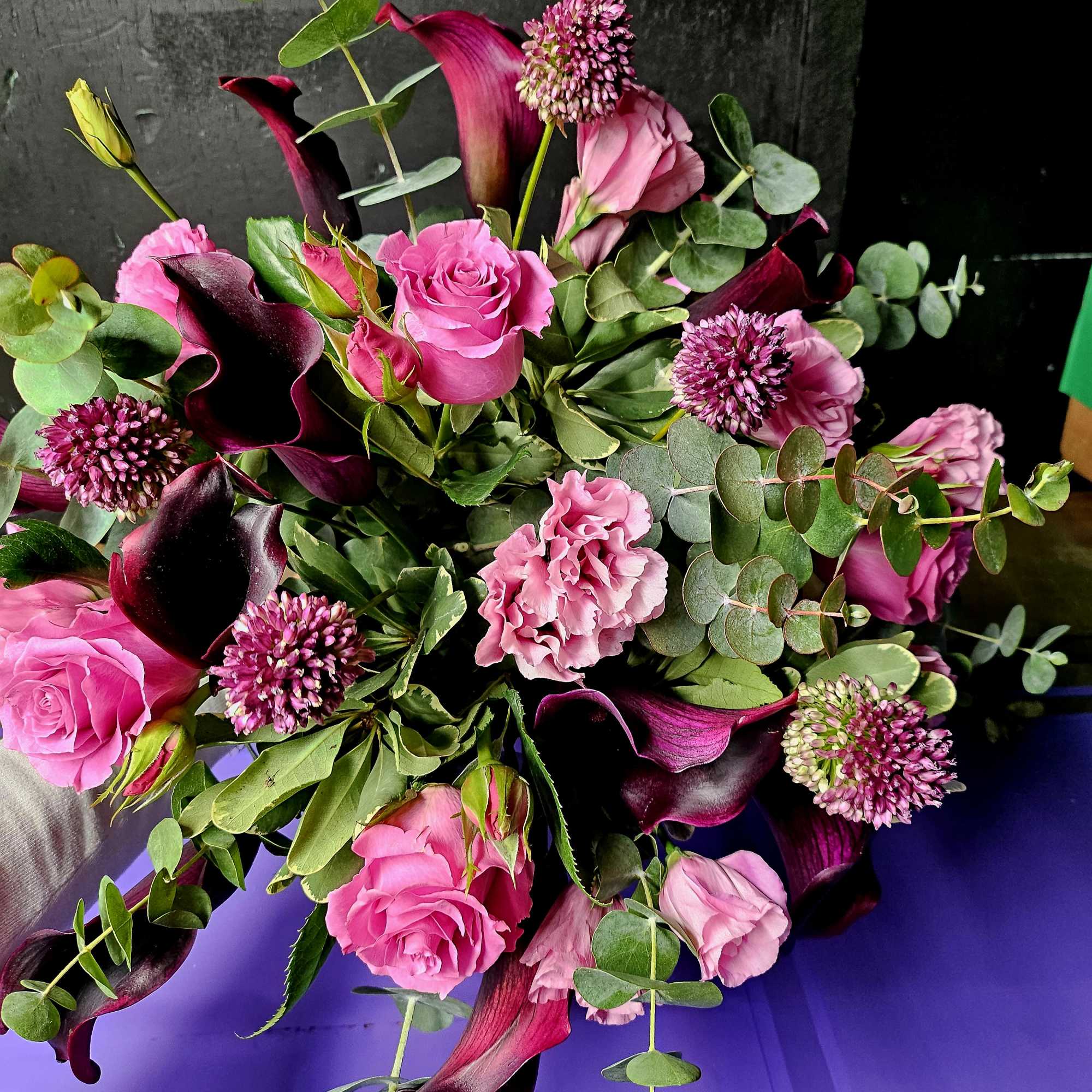 Bouquet of pink roses, calla lilies, and purple blooms with eucalyptus