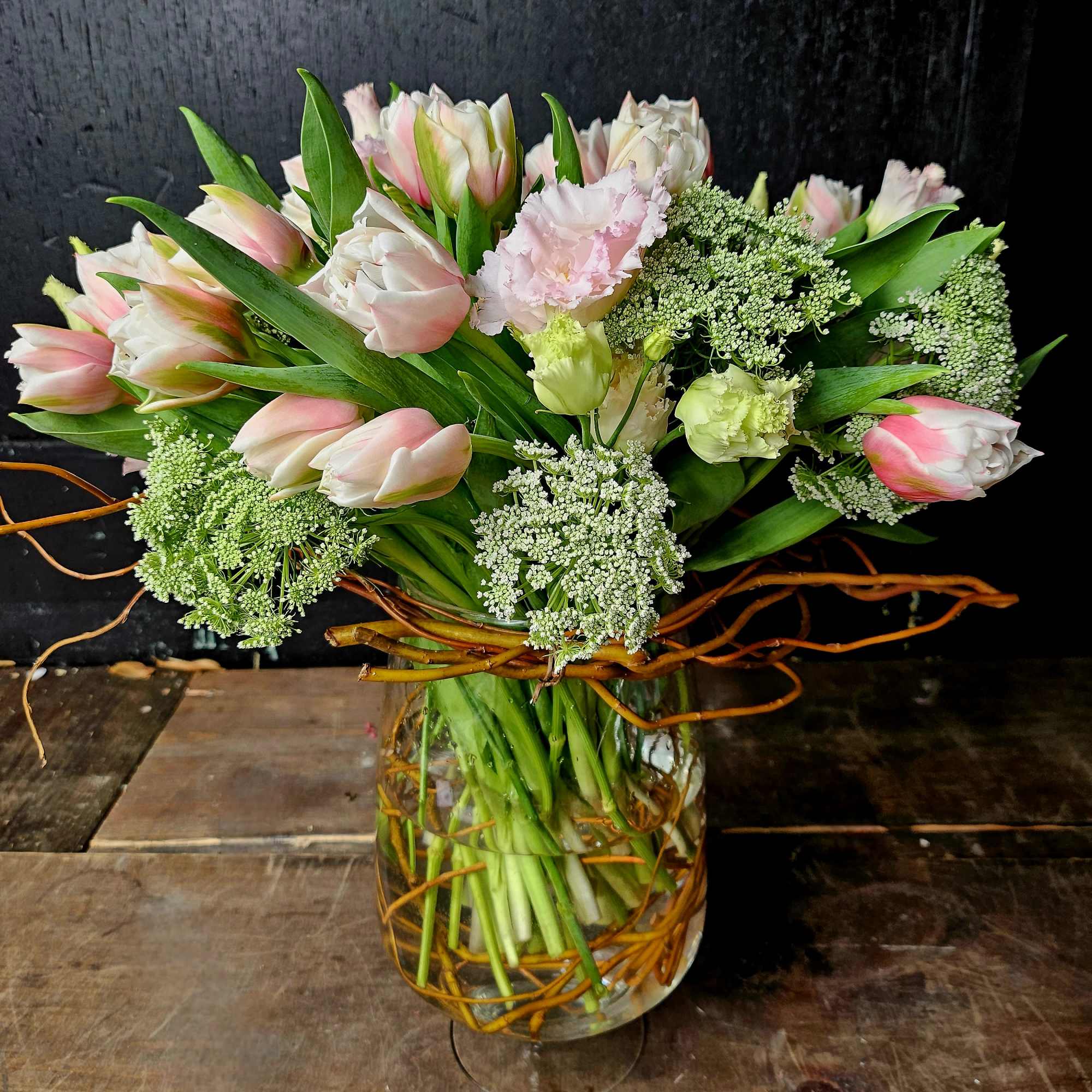 Pink and white tulips with pale green blooms in a glass vase