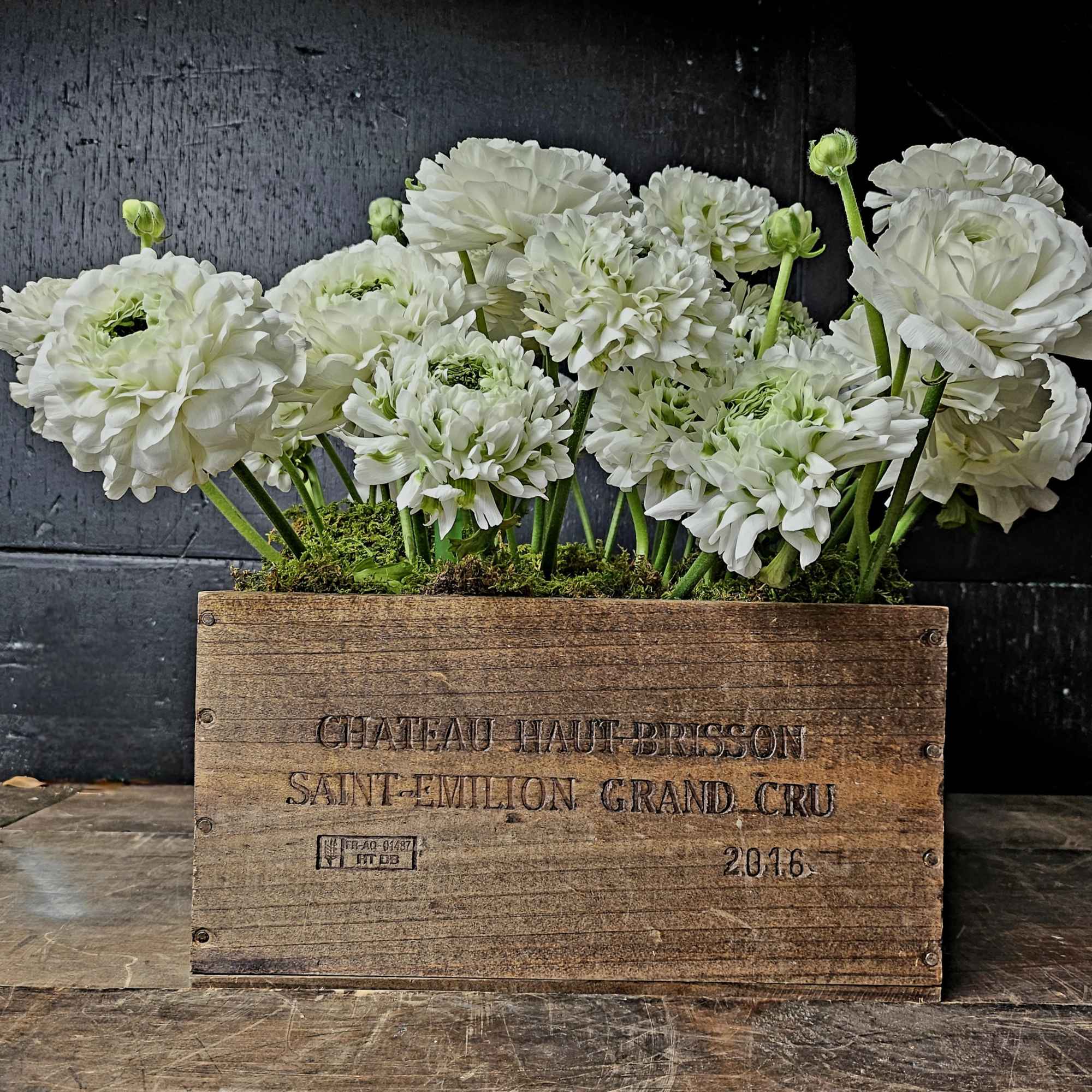 White ranunculus flowers arranged in a wooden crate