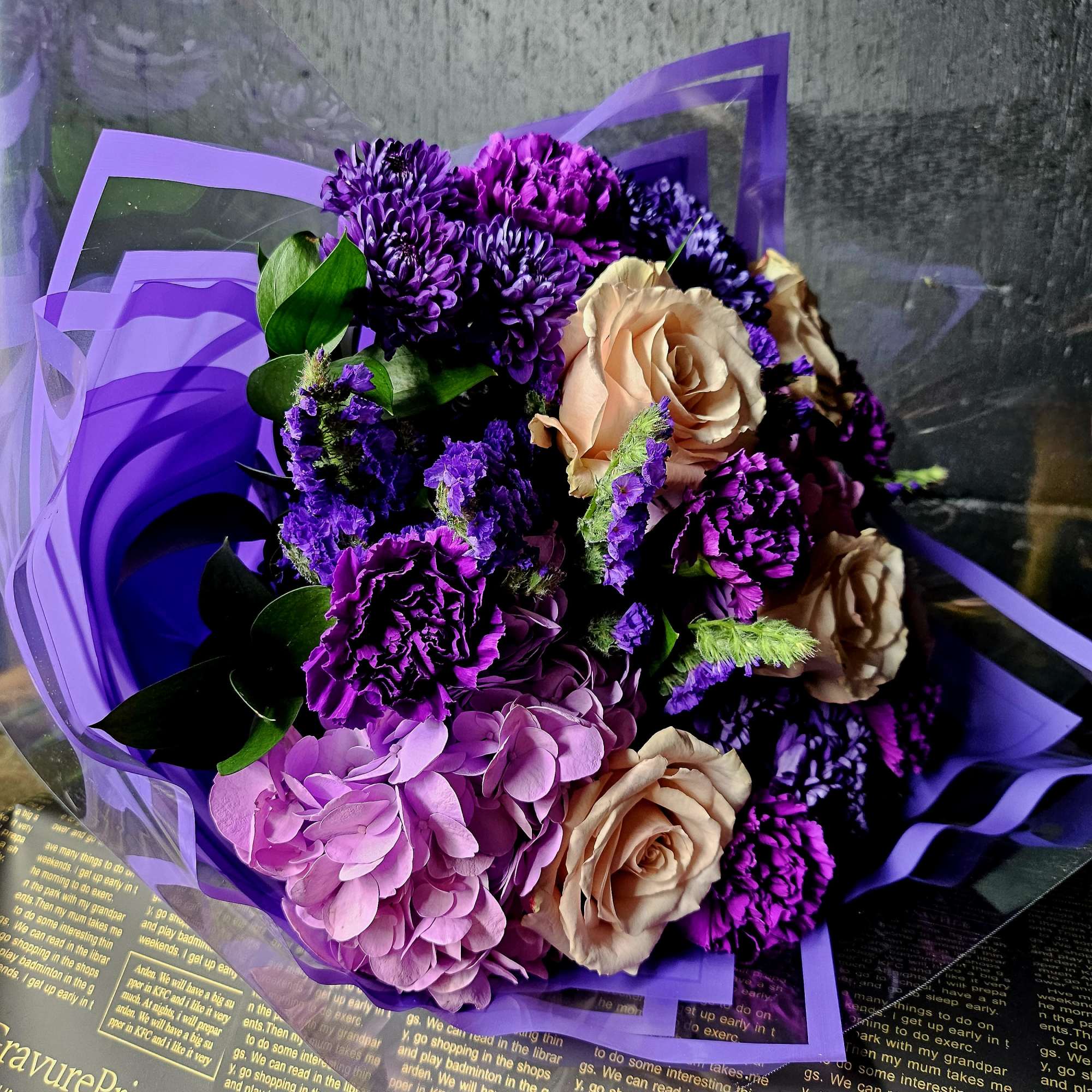 Bouquet of purple and peach flowers wrapped in lavender paper