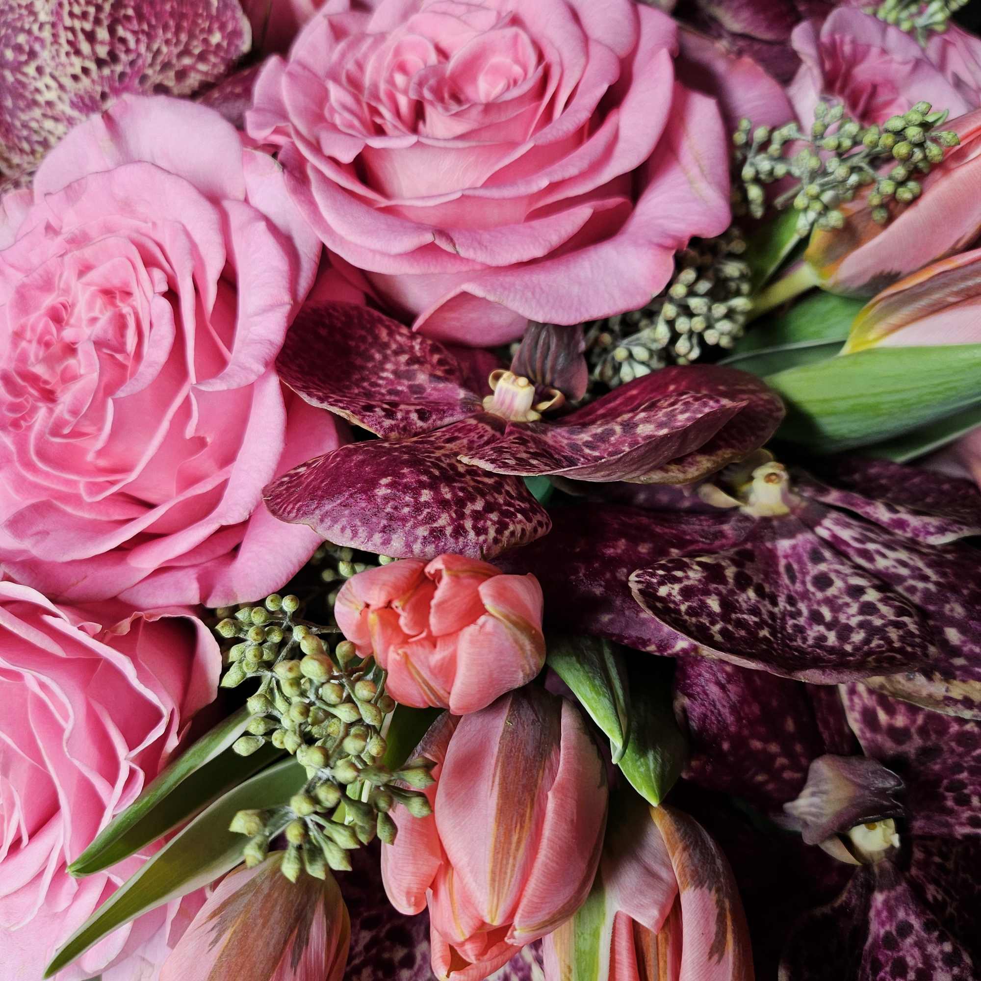 Pink roses with purple orchids and tulips in a close bouquet