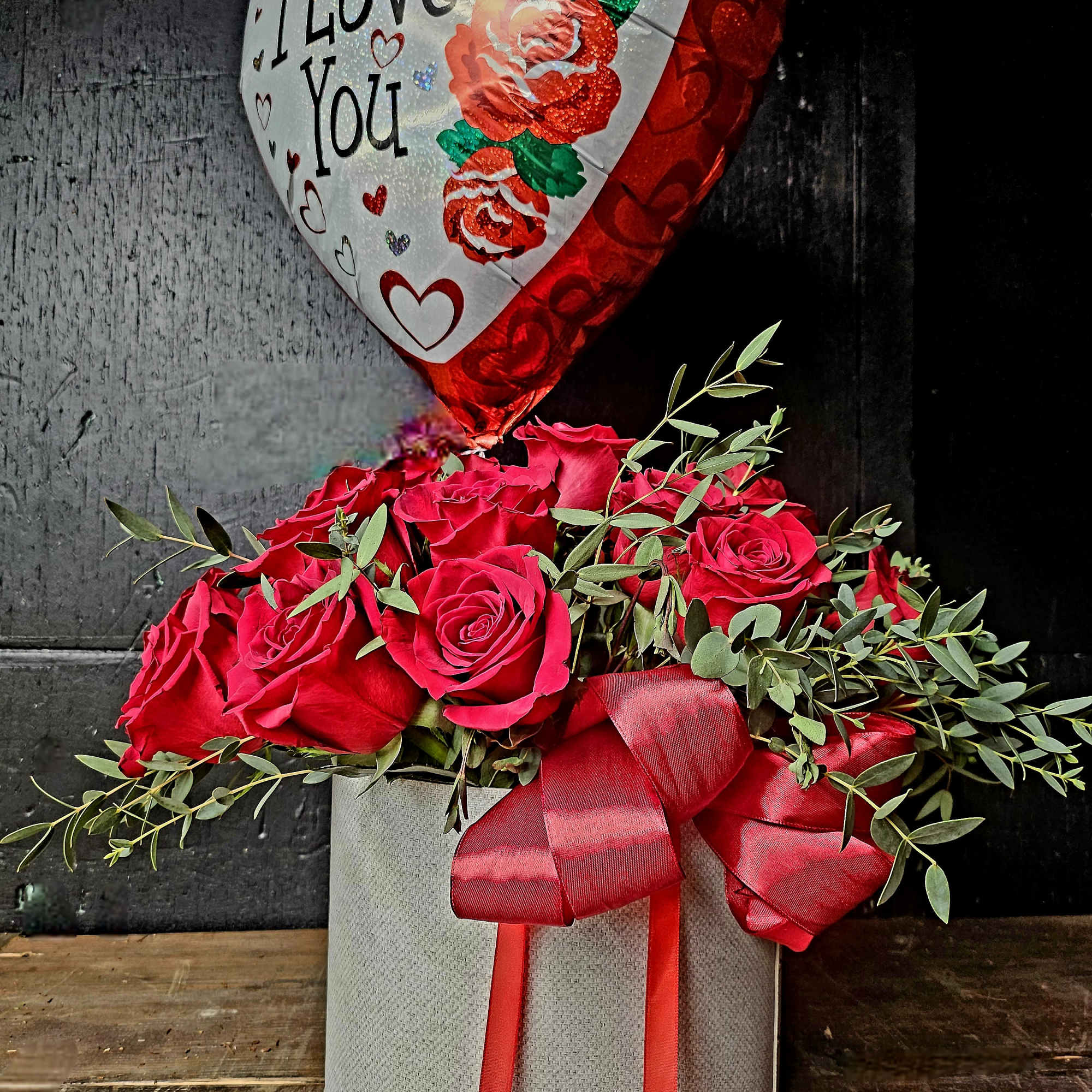 Red rose arrangement in a gray box with a heart-shaped "I Love You" balloon