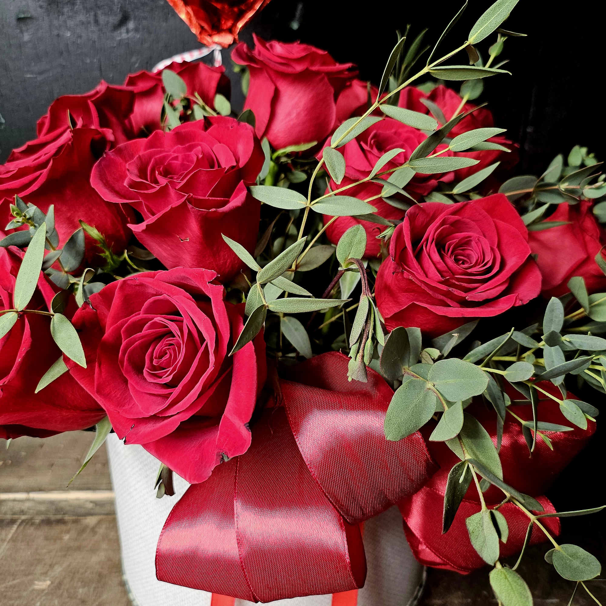Red roses in a white hatbox with a red ribbon