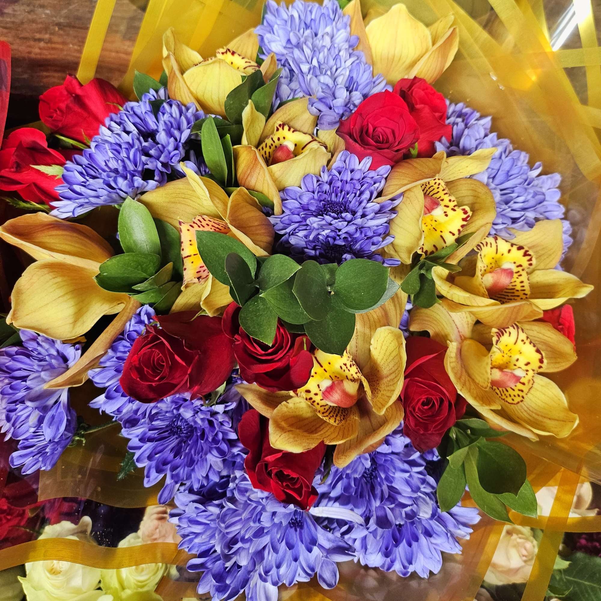 Bouquet of red roses, purple chrysanthemums, and yellow orchids