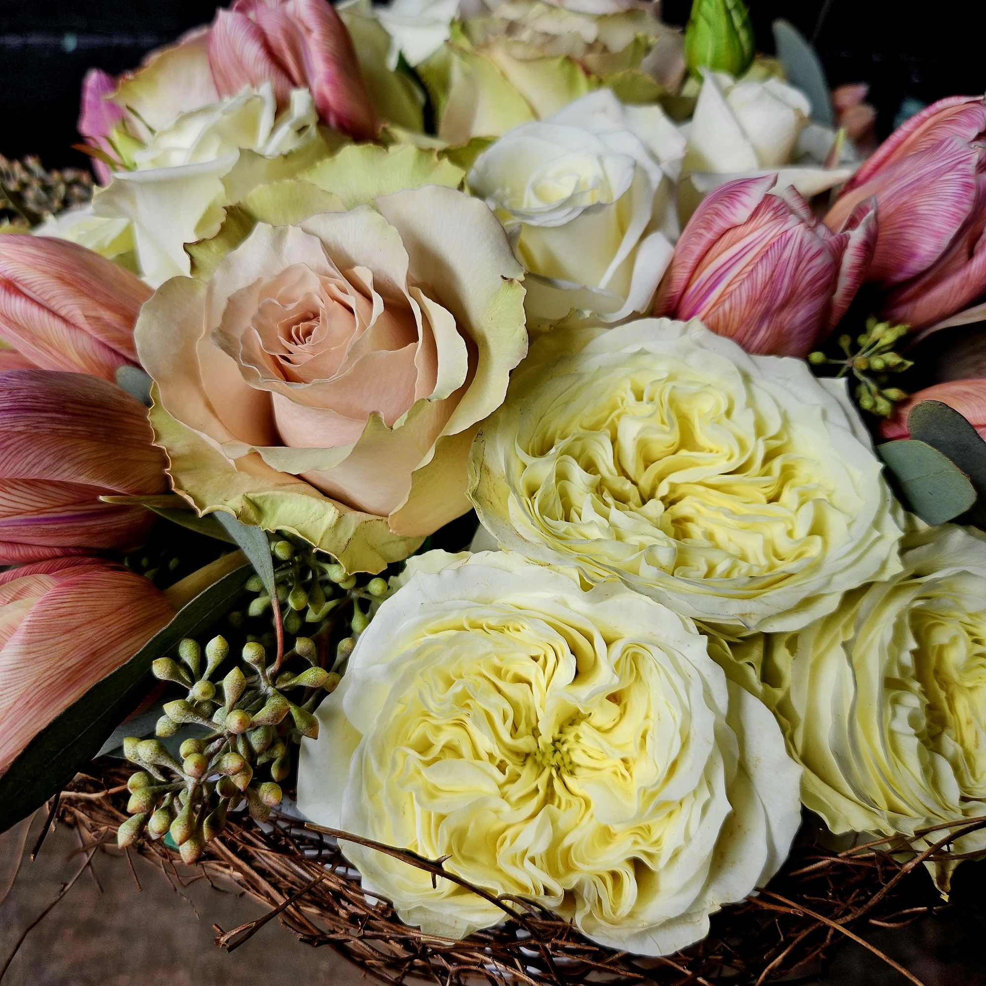 Bouquet of cream and blush roses with pink tulips in a woven basket