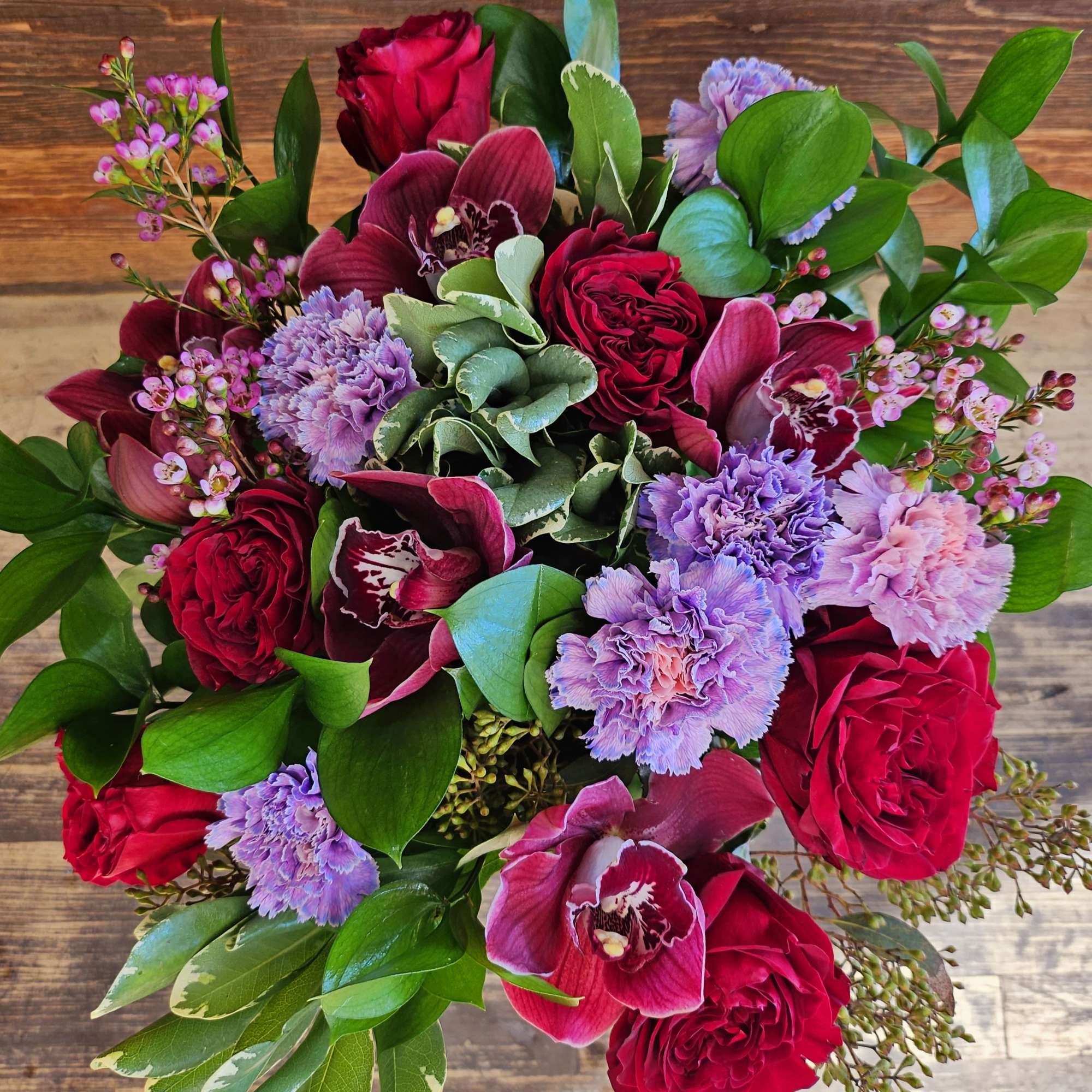 Bouquet of red roses, purple orchids, and lavender carnations