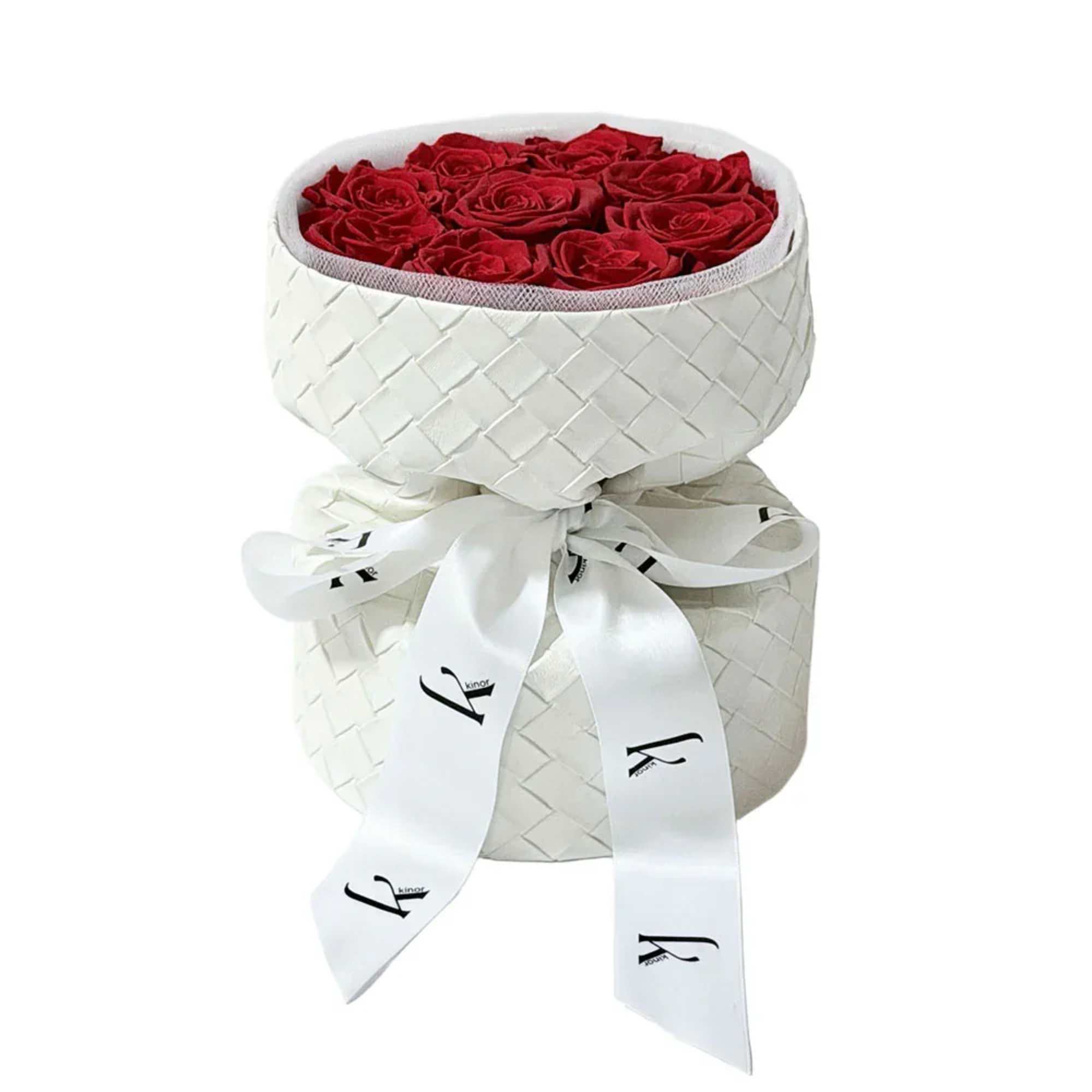 Red roses arranged in a white woven hatbox with a ribbon bow