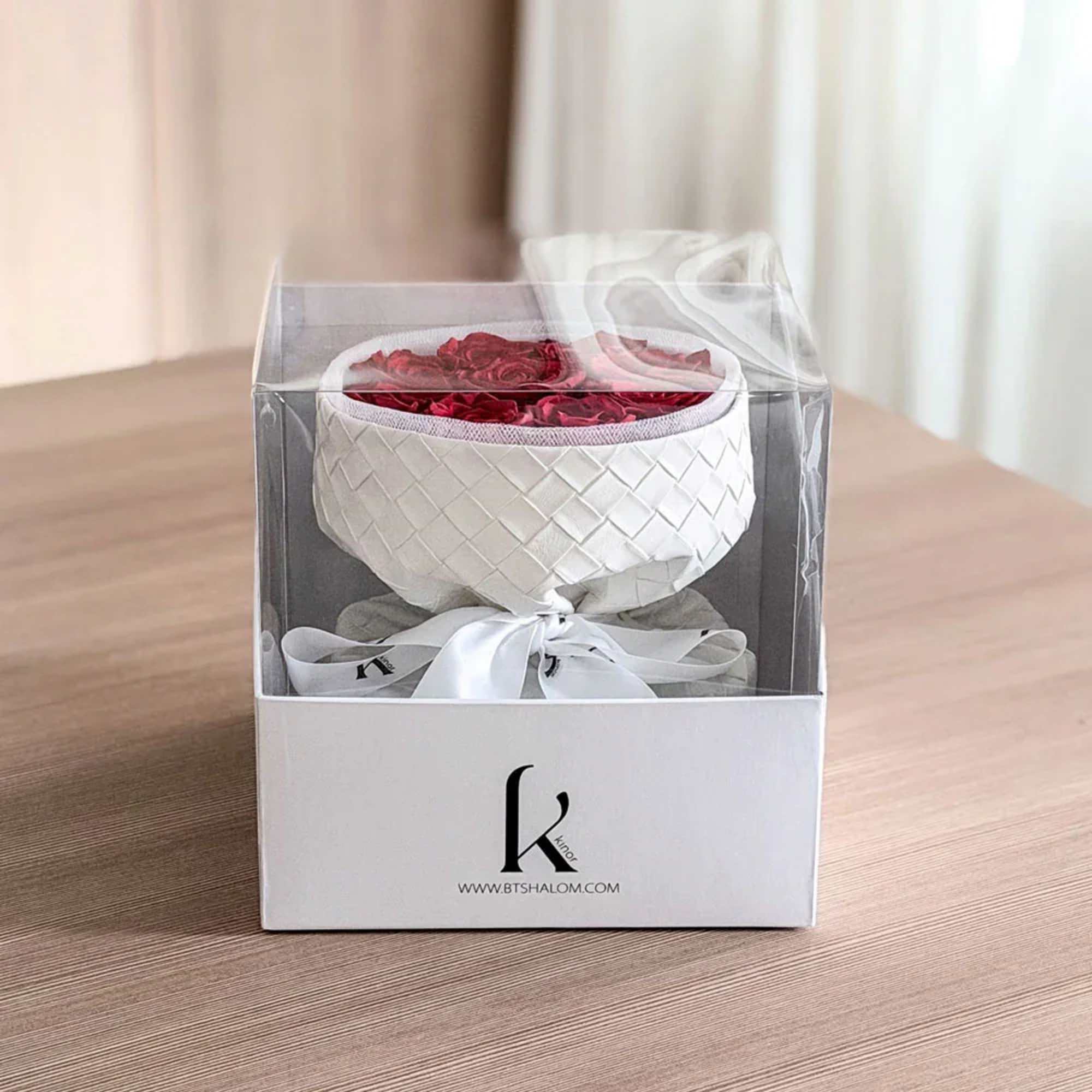 White gift box with red rose petals inside a clear lid