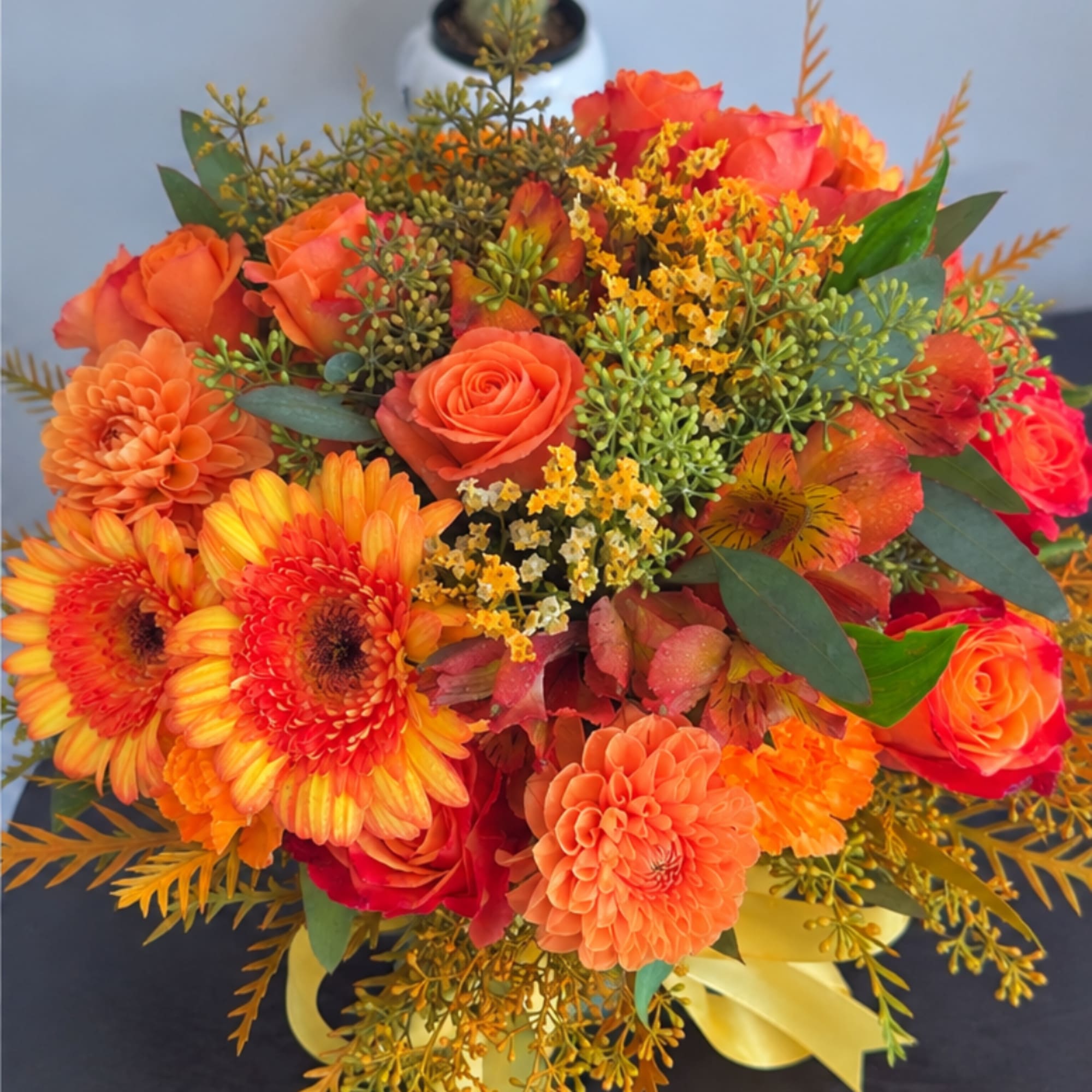 Orange and red mixed bouquet with roses and daisies in a yellow ribbon wrap