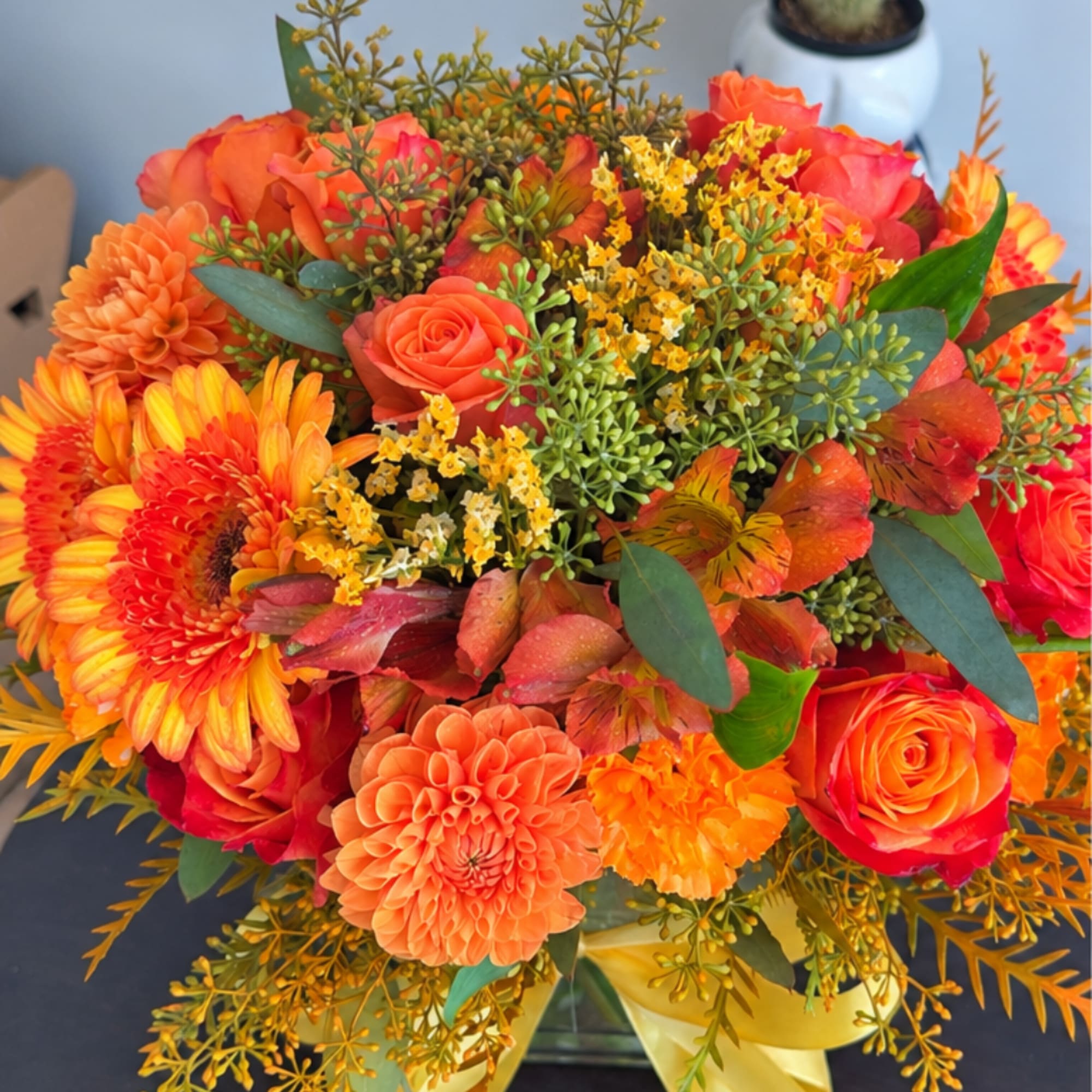 Orange and red mixed flower bouquet with roses and daisies in a vase