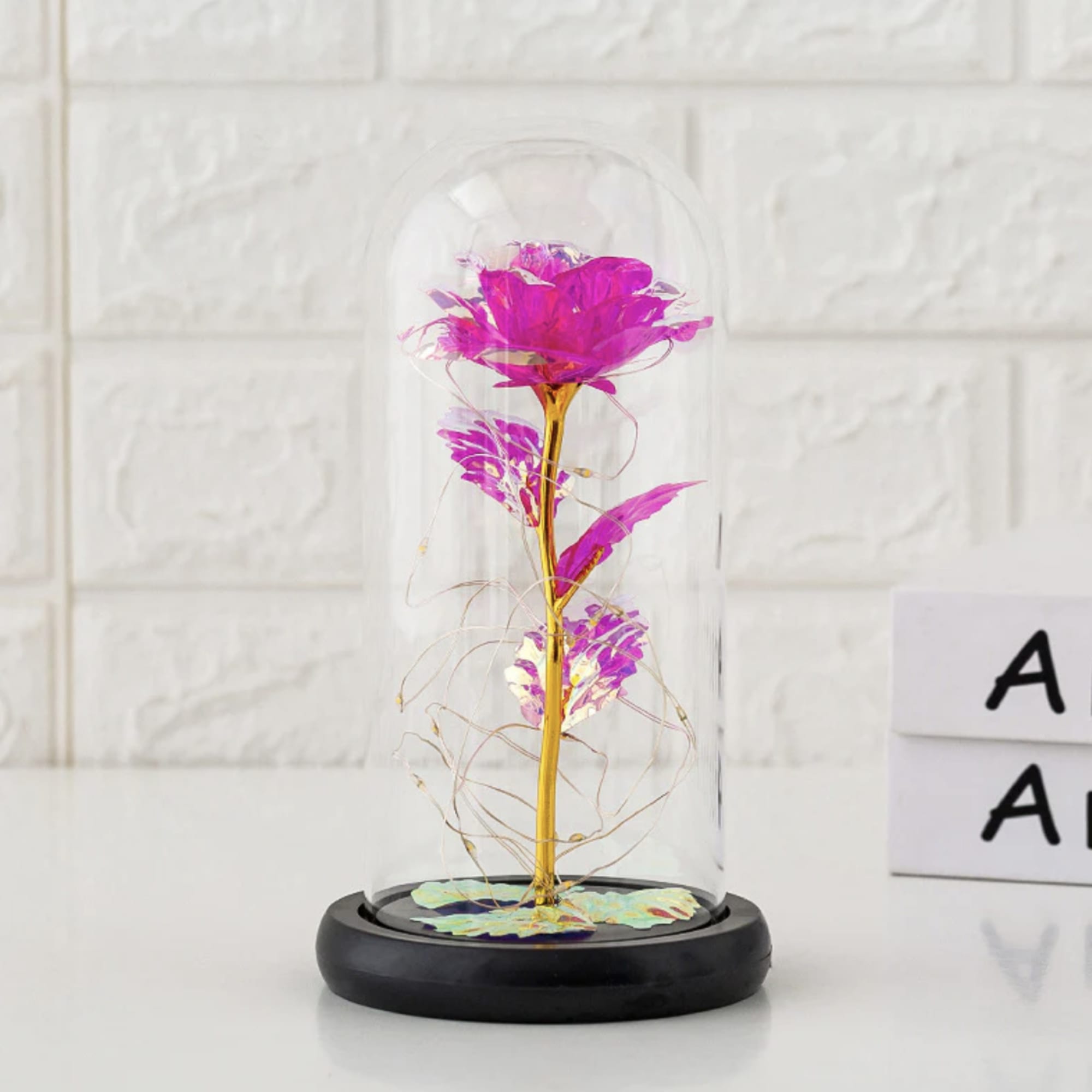 Single pink flower under a glass dome on a black base
