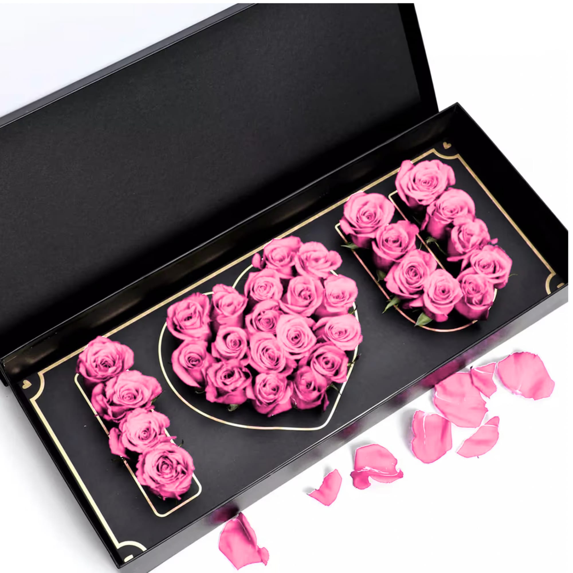 Pink roses arranged in a black gift box with loose petals