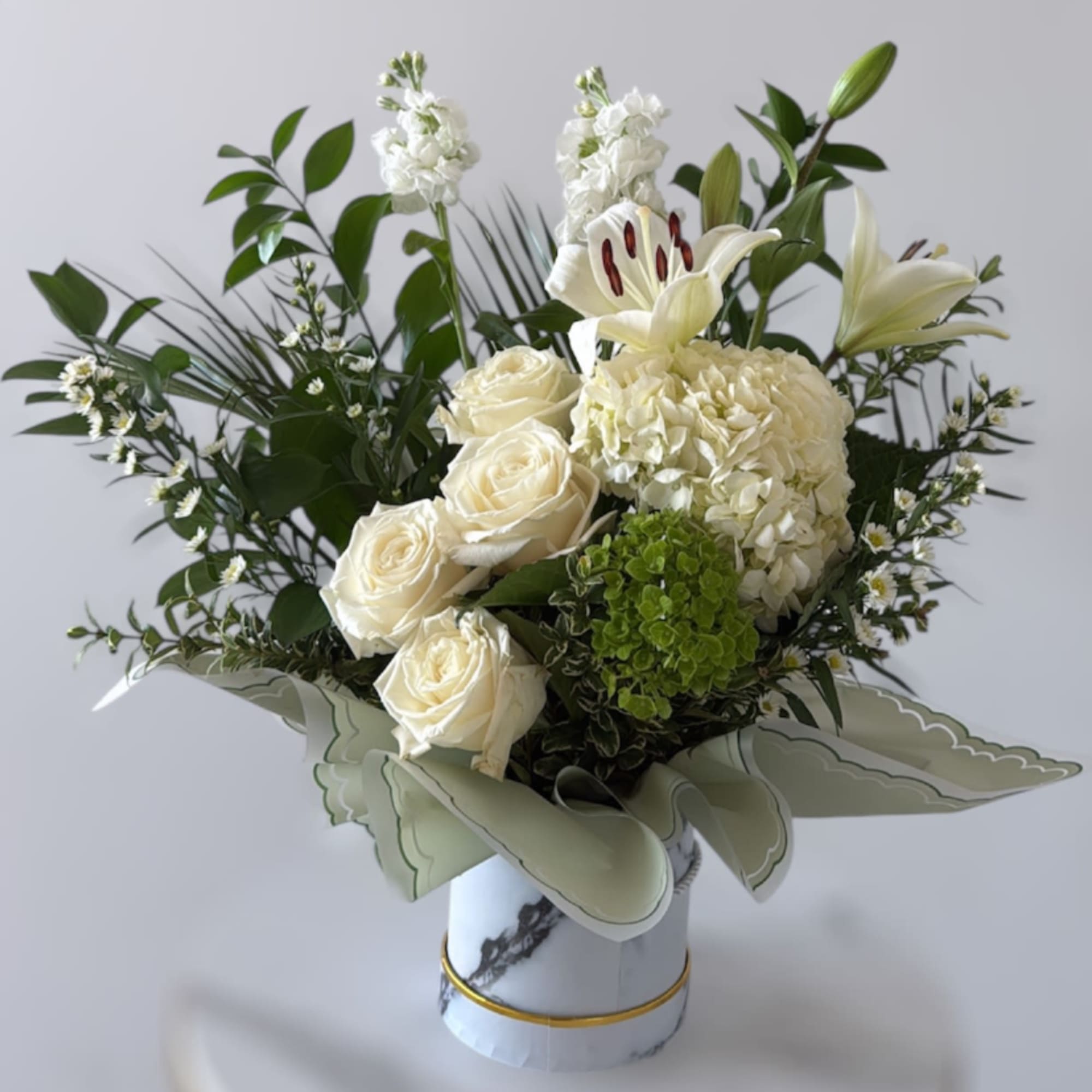 White roses, lilies, and hydrangea in a decorative vase
