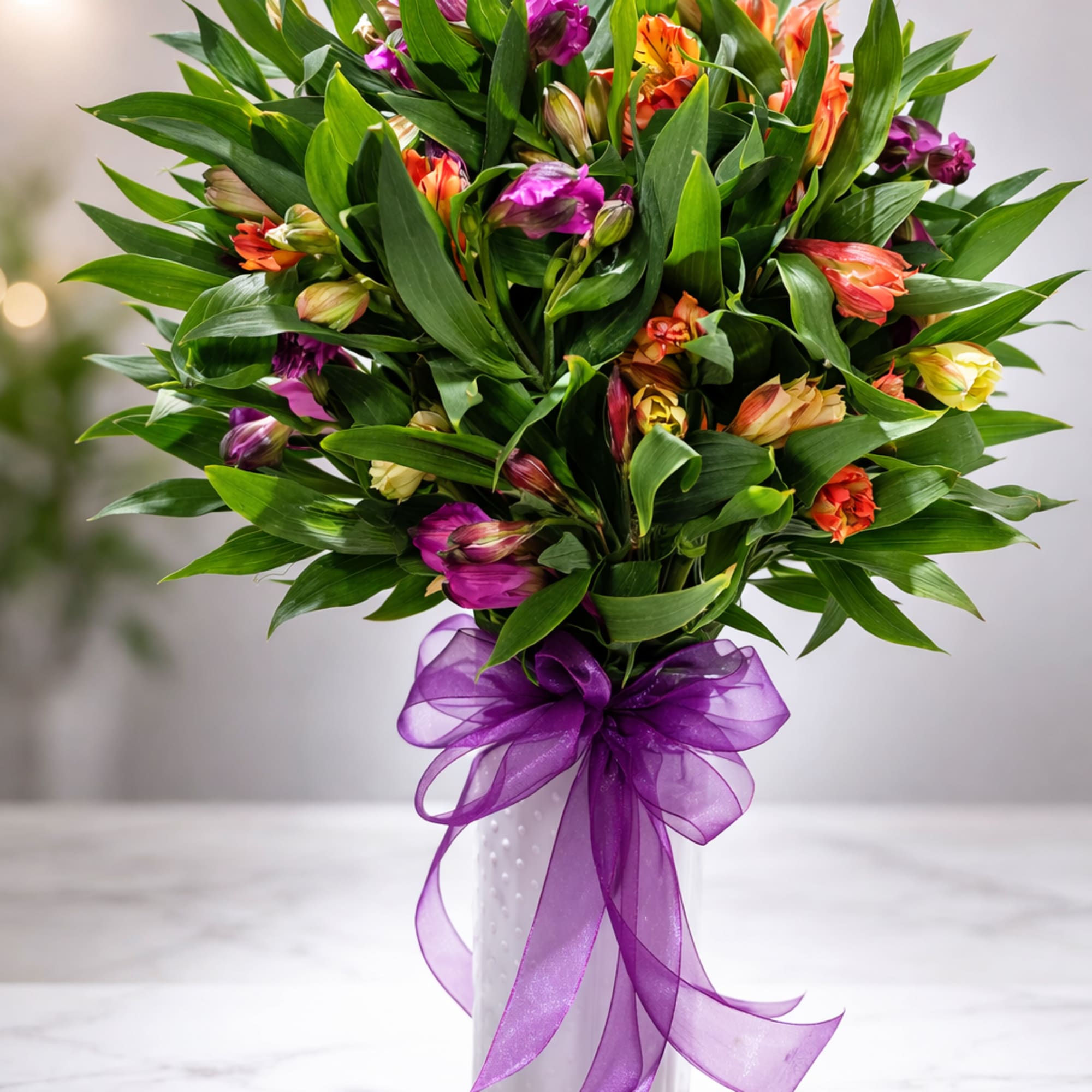 Bouquet of multicolored flowers in a white vase with a purple ribbon