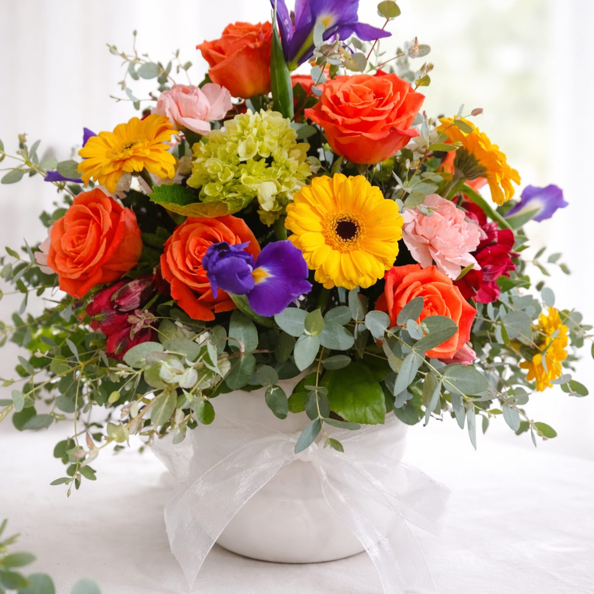 Colorful mixed bouquet in a white vase with a sheer ribbon