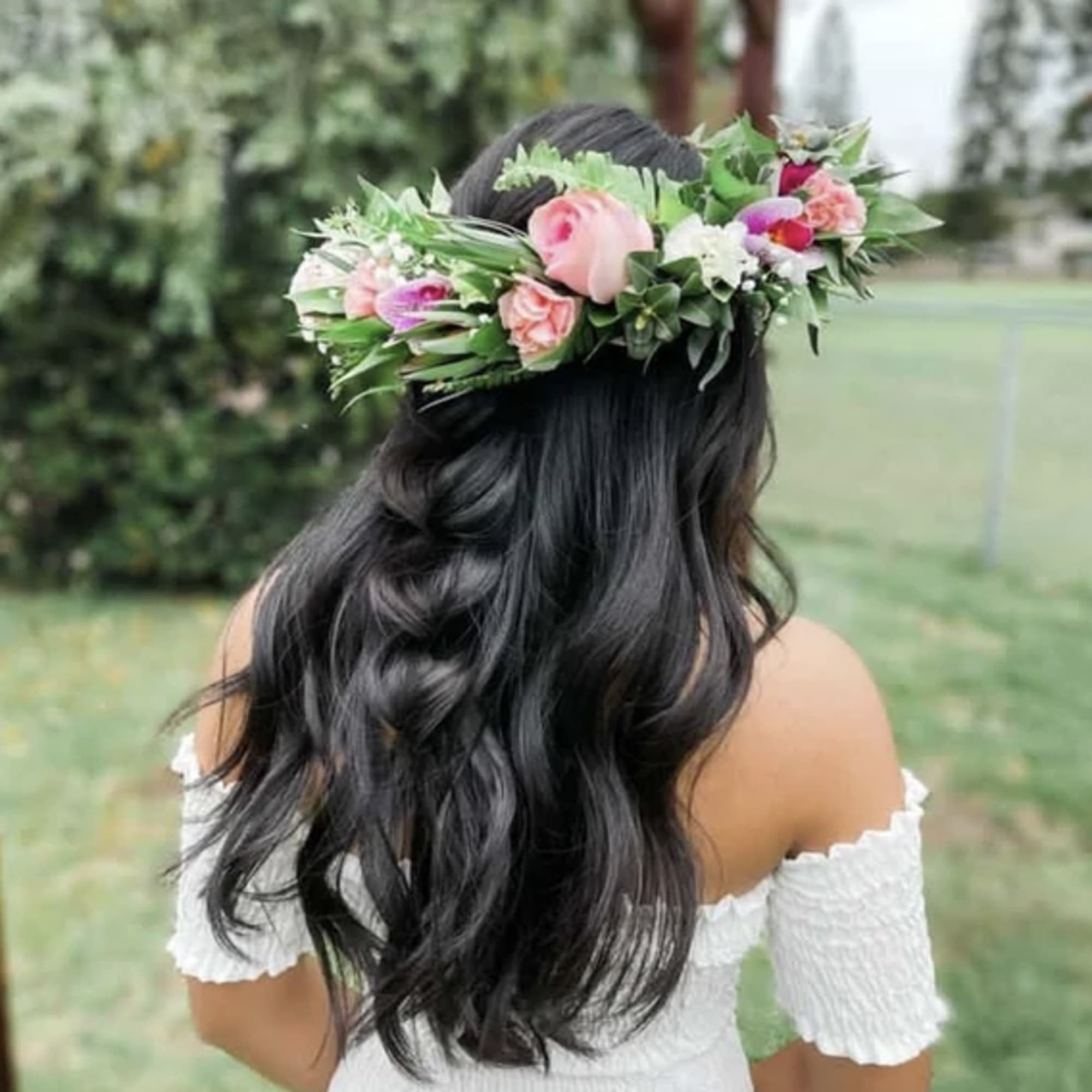 Woman wearing a pink and white rose flower crown viewed from behind outdoors