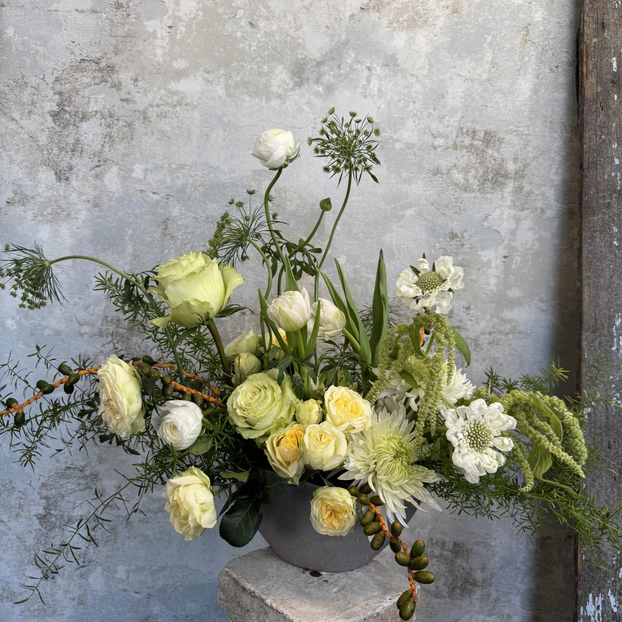 White and pale yellow floral arrangement in a gray vase