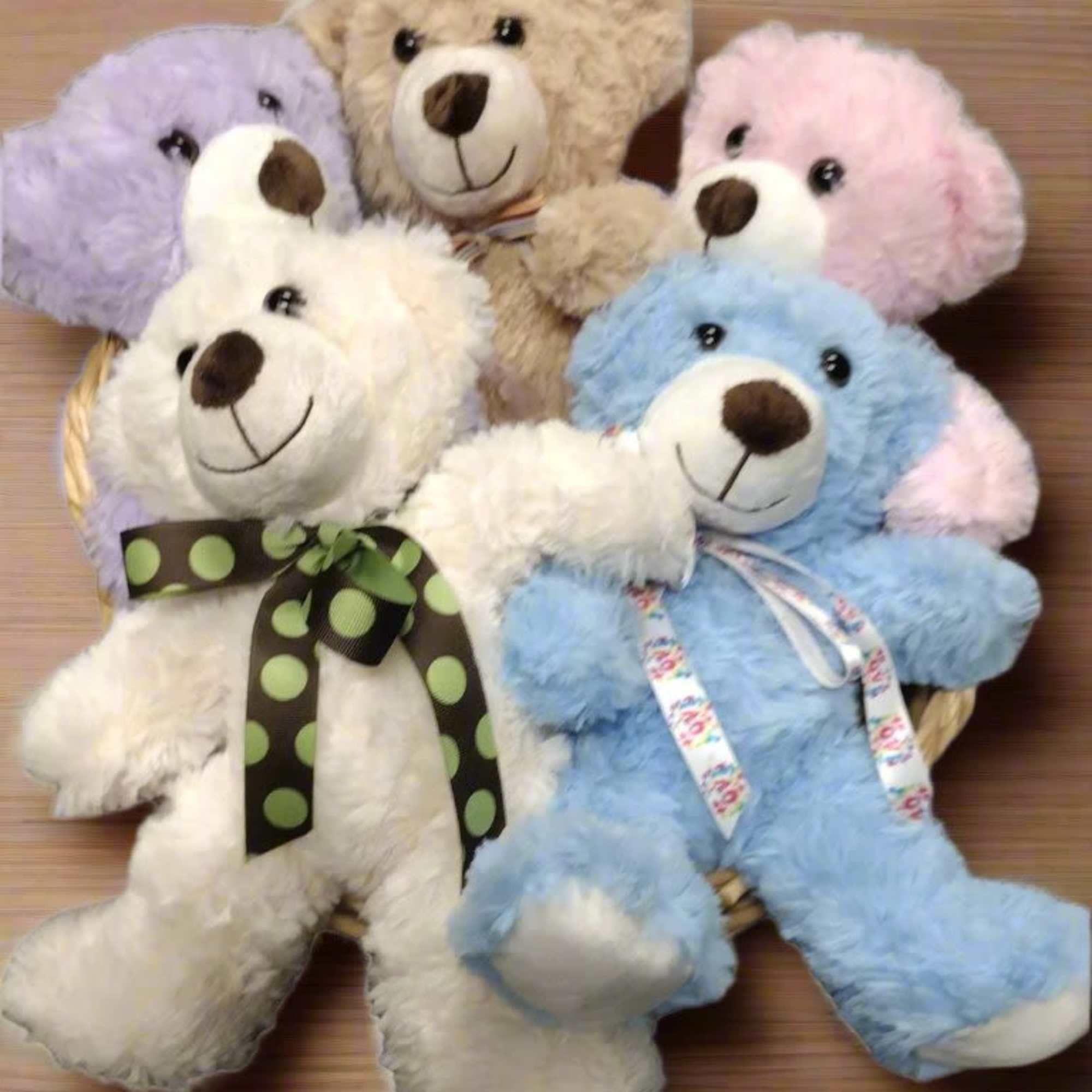 Five plush teddy bears in pastel colors arranged in a basket
