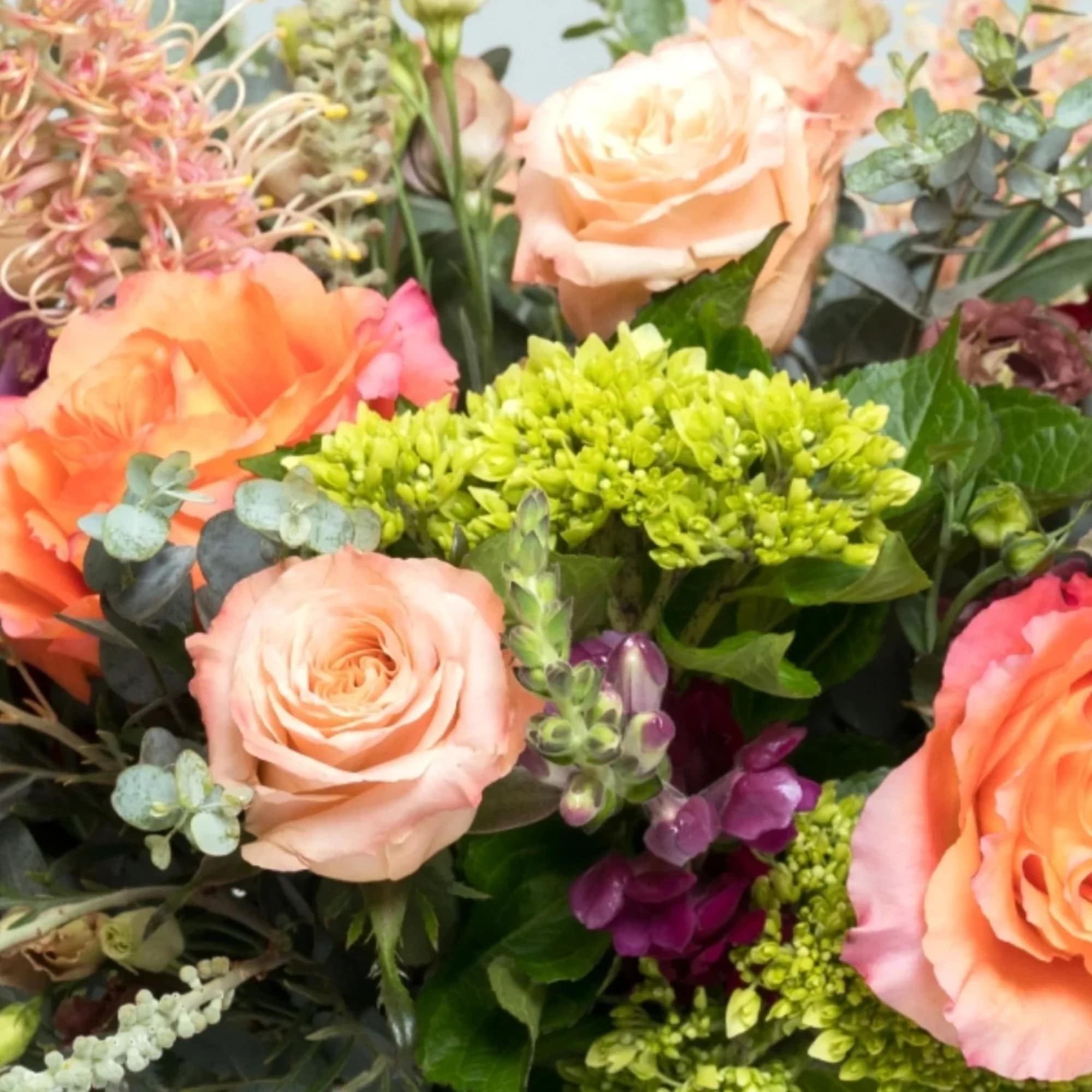 Bouquet of peach roses with green and purple flowers