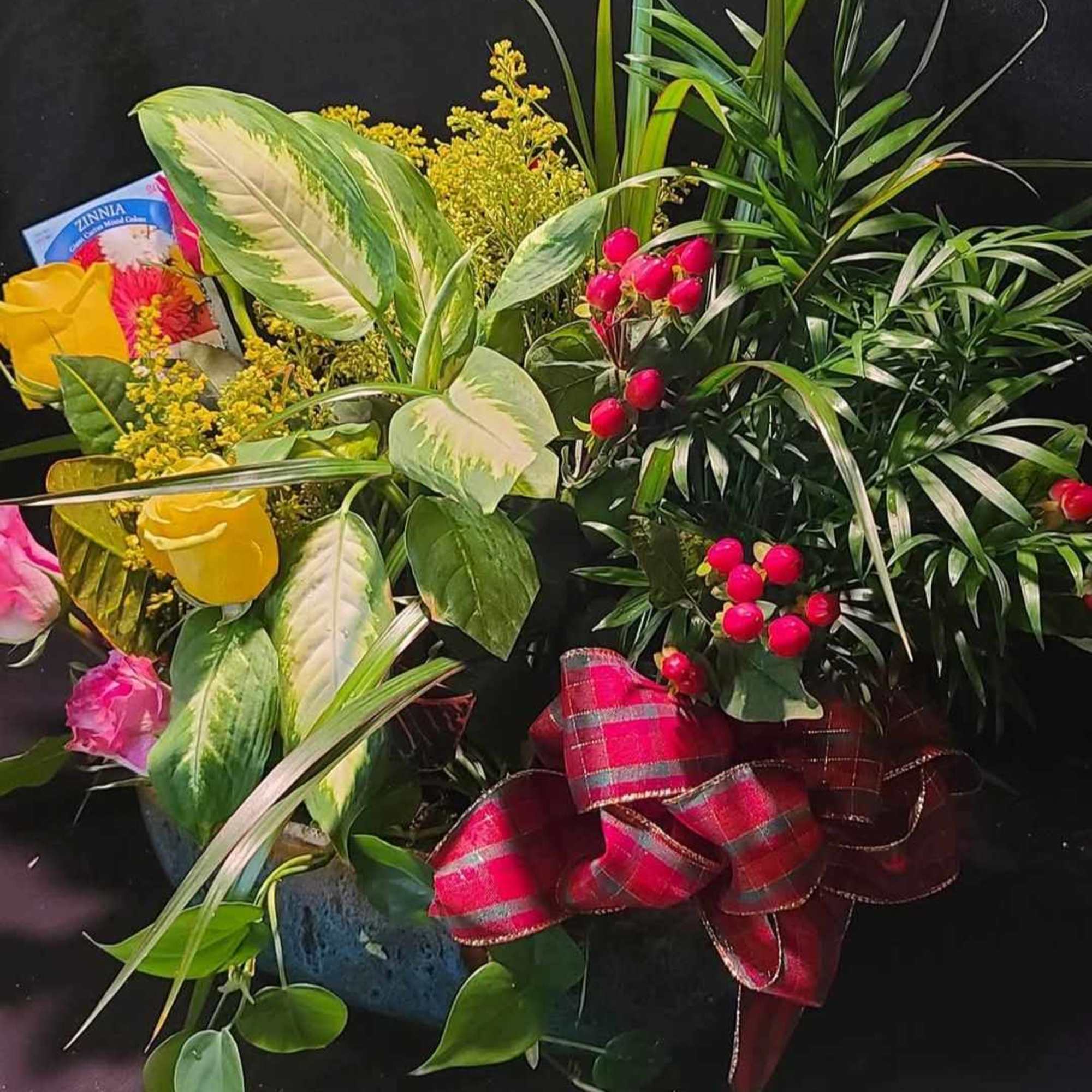 Mixed bouquet with yellow and pink flowers in a container, accented by a red plaid ribbon.