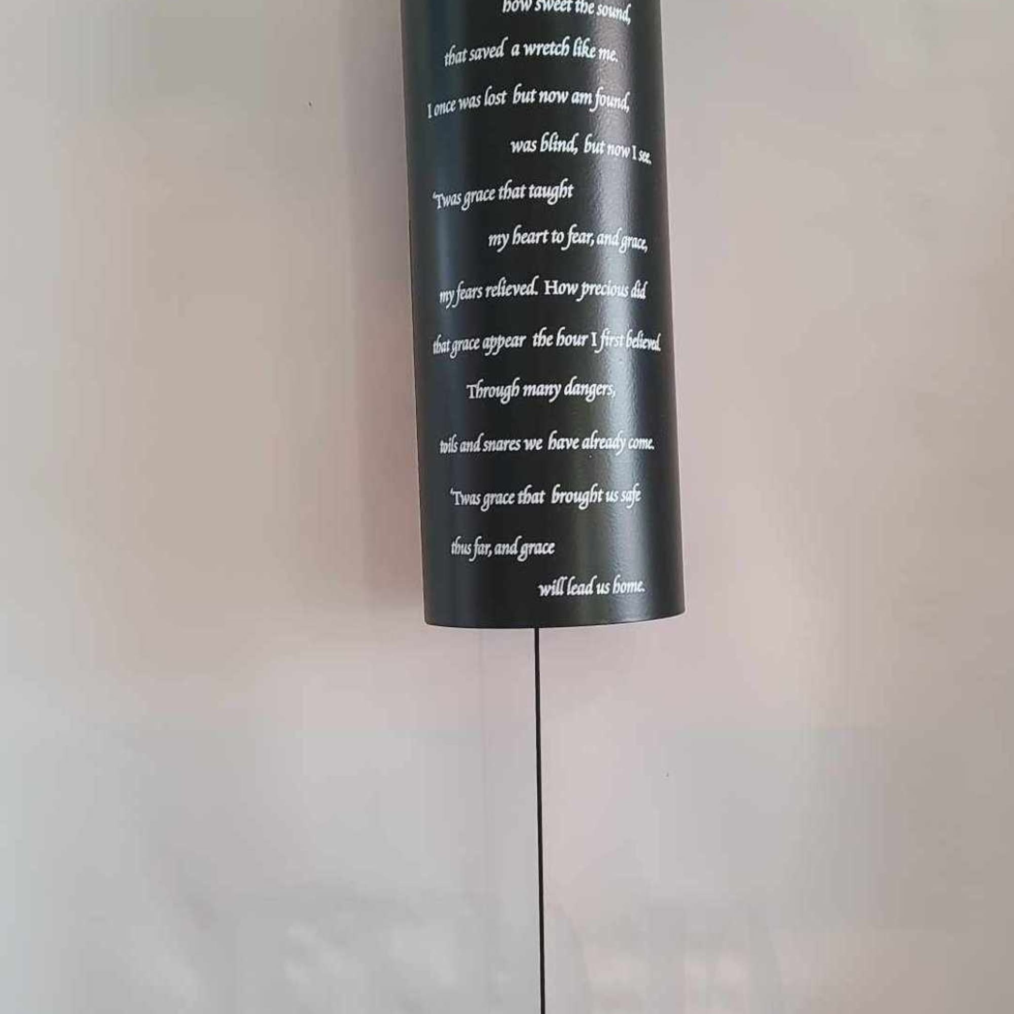 Black hanging wind chime with white text and a round black clapper