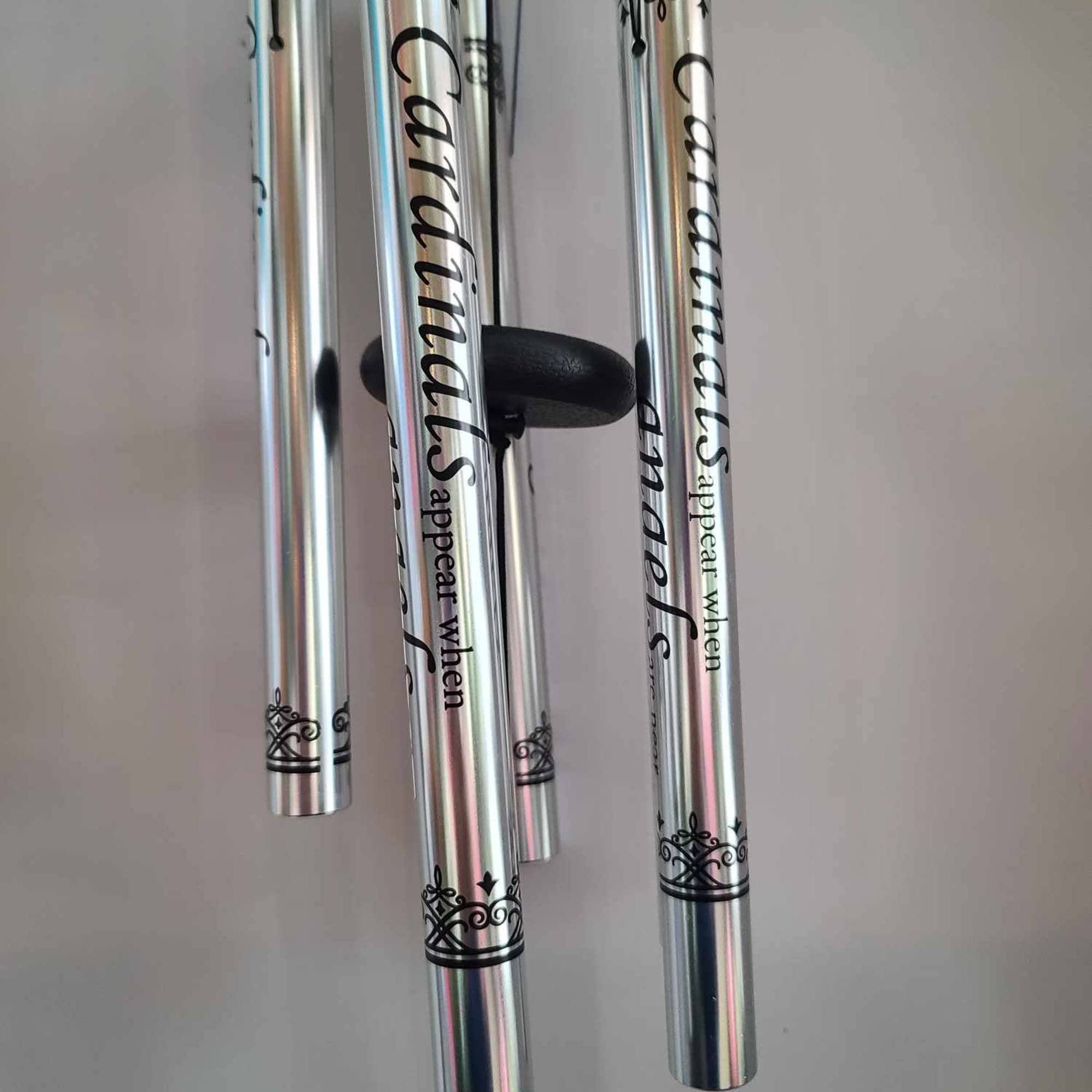 Silver wind chimes with black decorative text and scrollwork