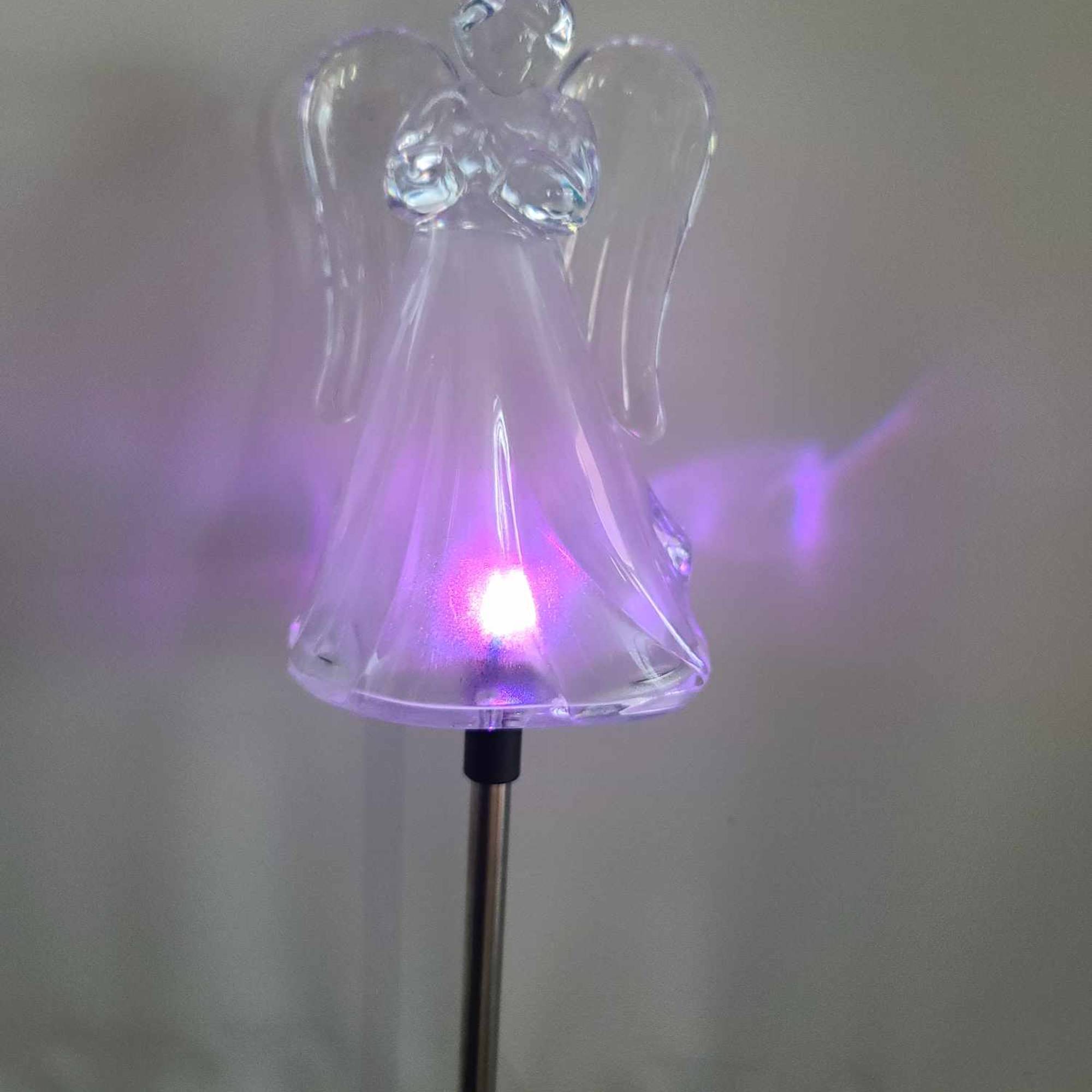 Clear angel figurine on a metal stake with a purple light inside