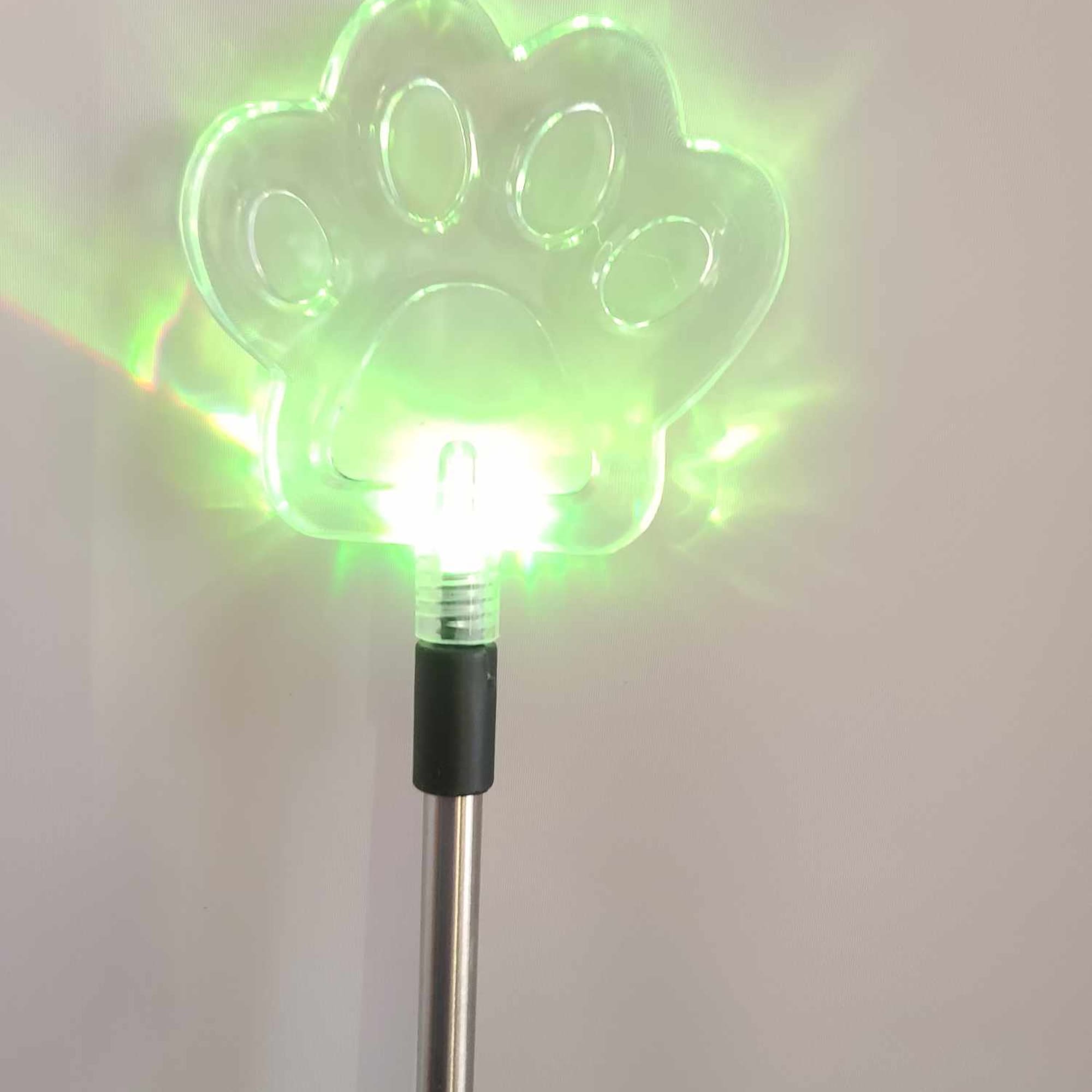 Glowing green paw-shaped light on a metal pole