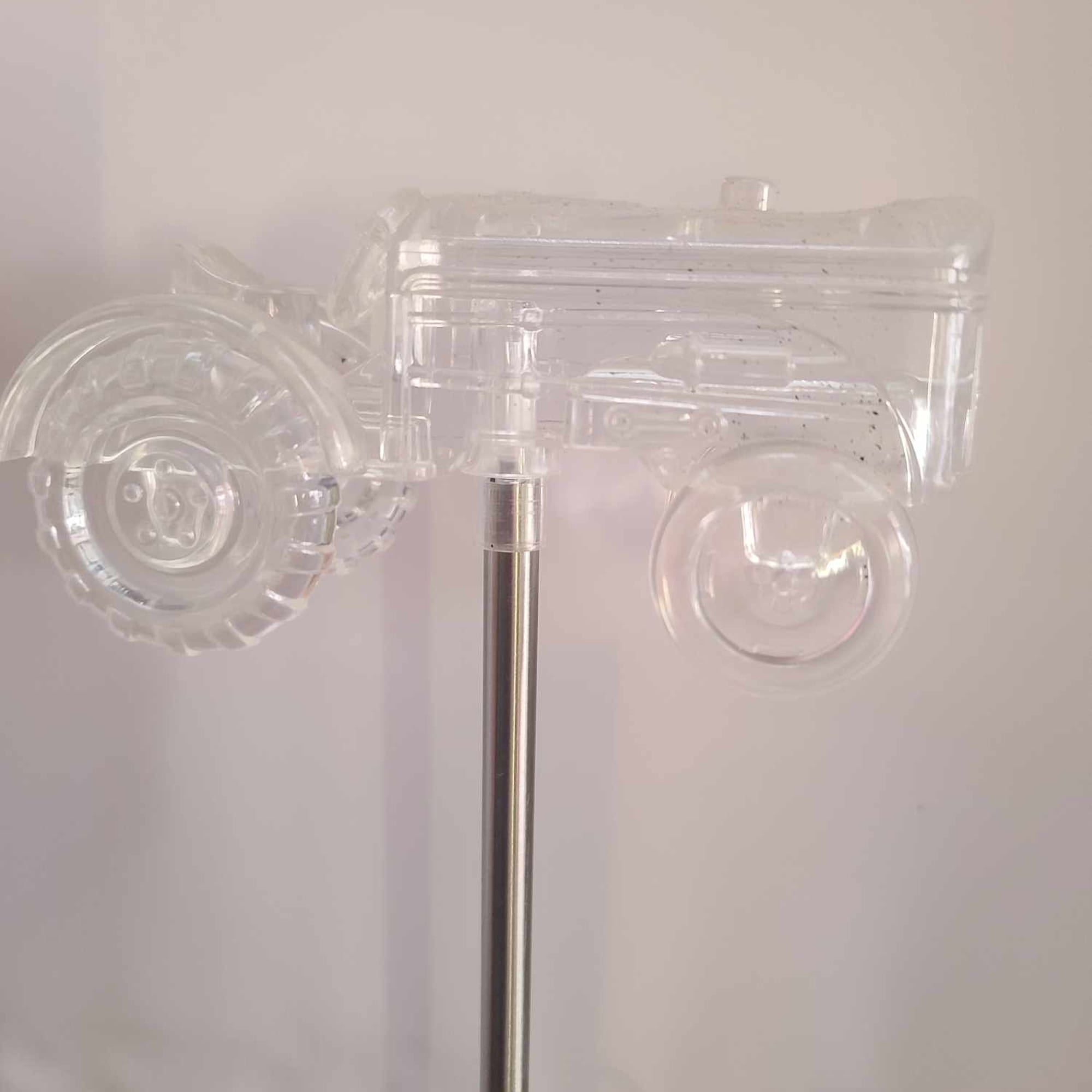 Clear plastic toy truck mounted on a metal pole against a plain wall