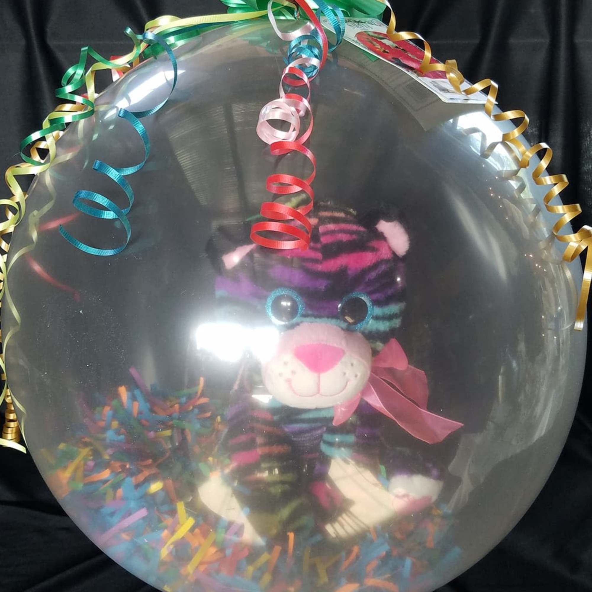 Clear balloon with a plush tiger and colorful curling ribbons