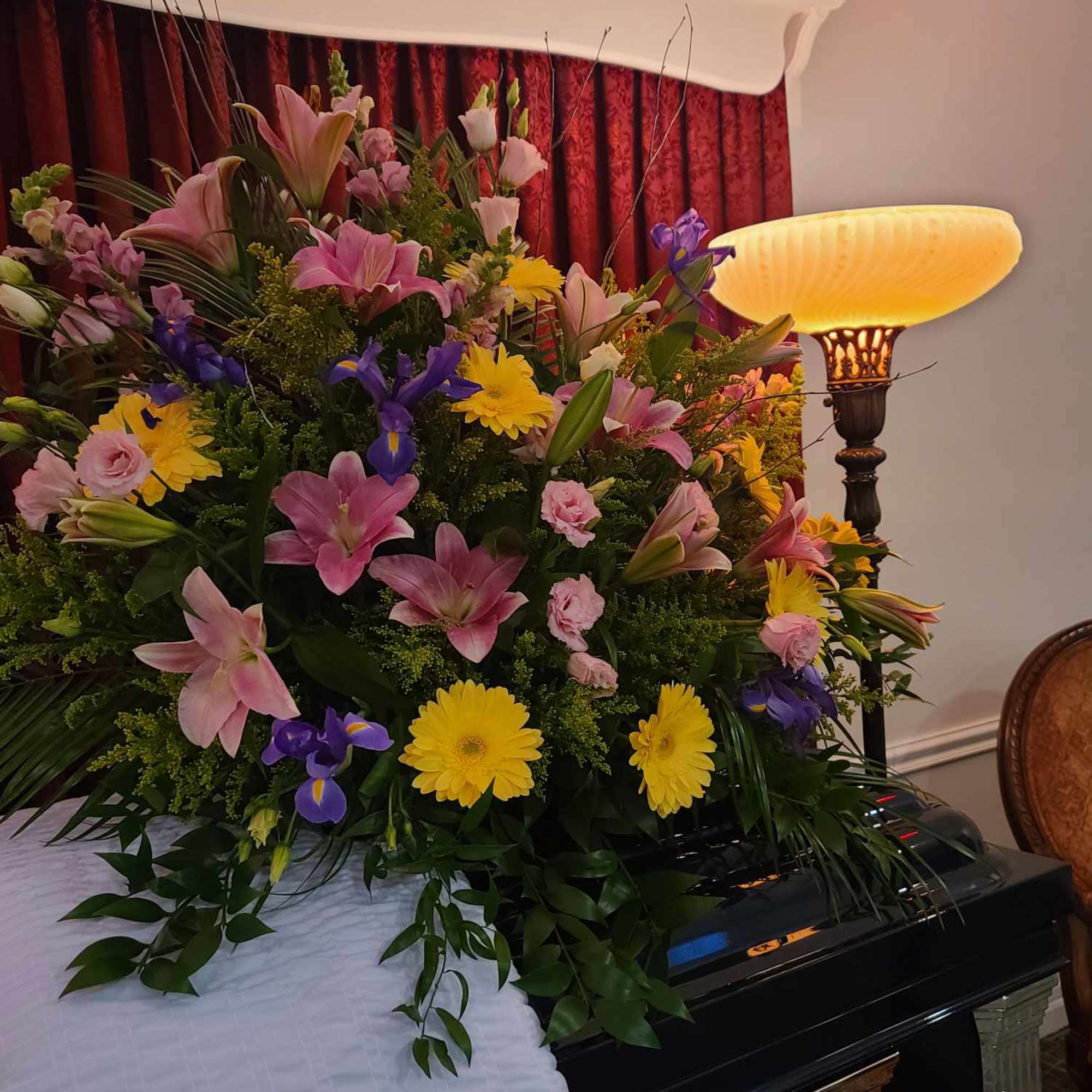 Large floral spray on a casket with pink, yellow, and purple flowers