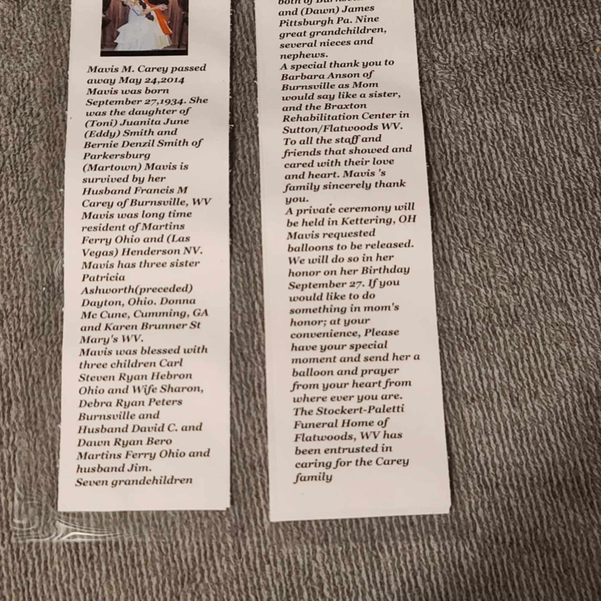 Two printed obituary bookmarks lie on a carpeted surface.