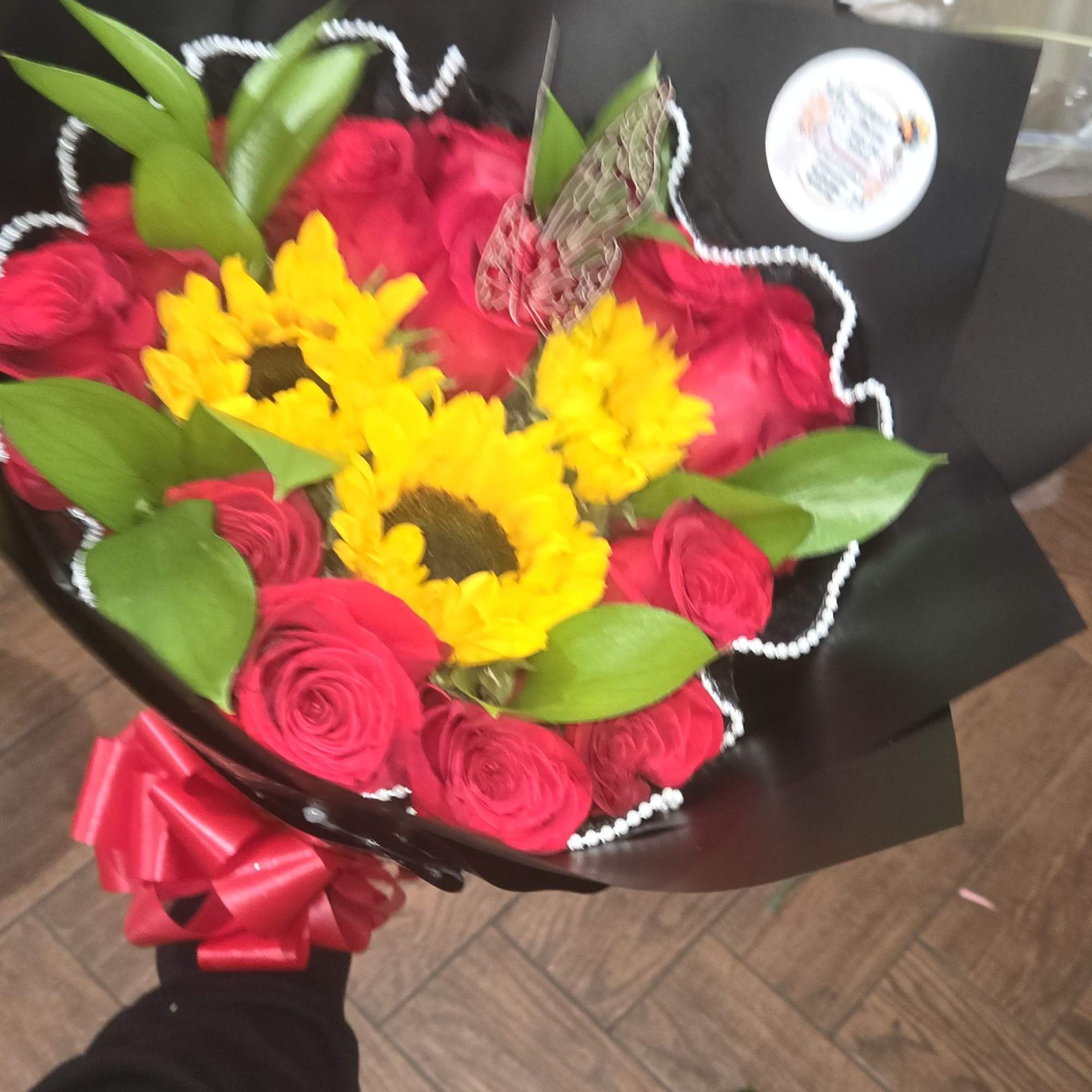 Bouquet of red roses and yellow sunflowers wrapped in black paper