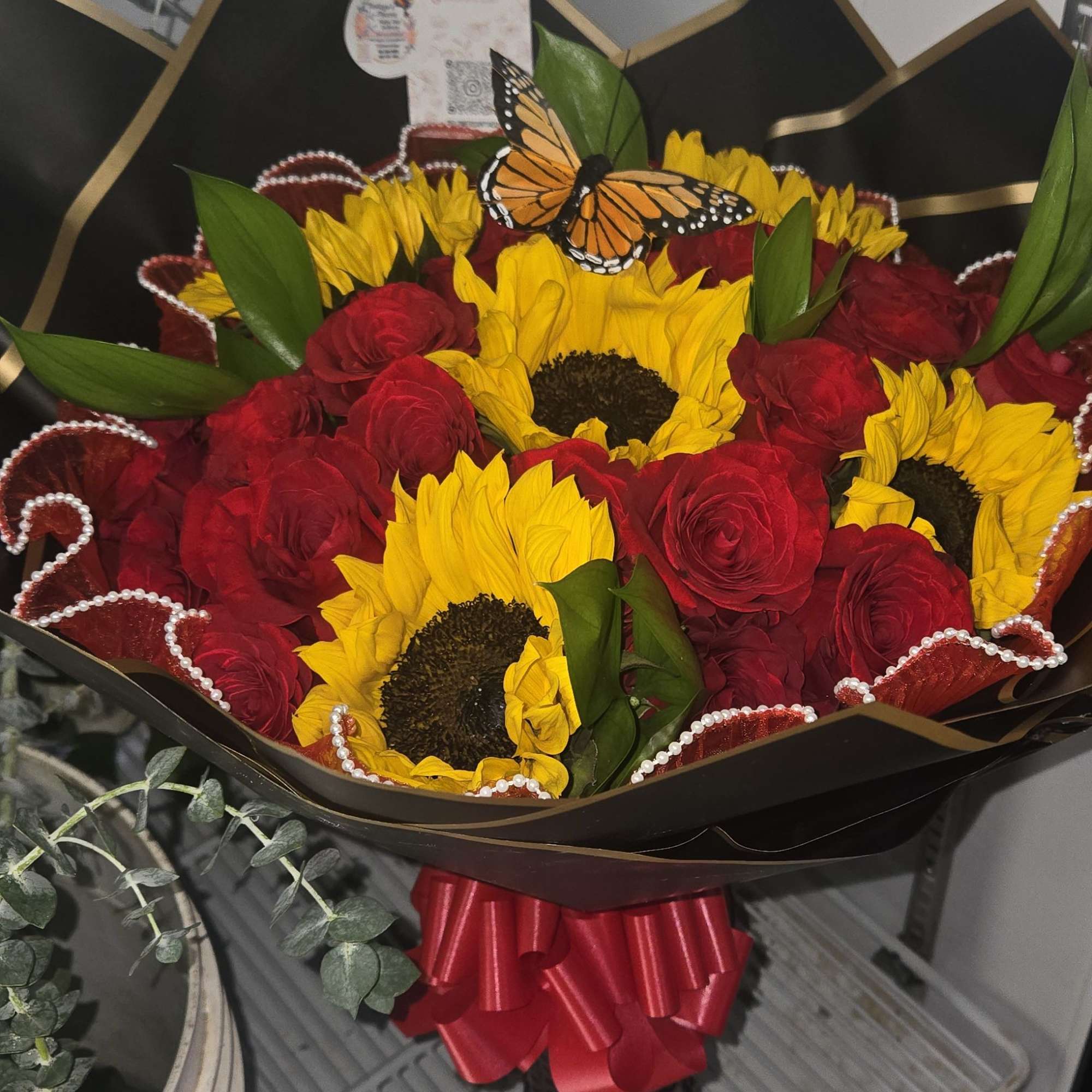 Bouquet of red roses and yellow sunflowers with a butterfly topper