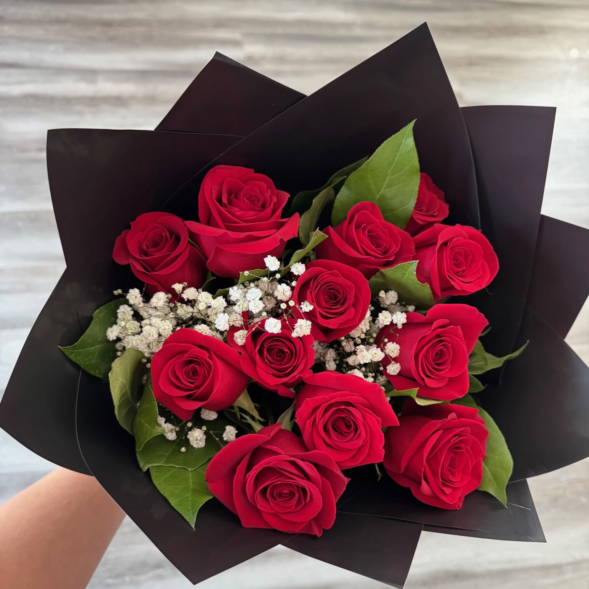 Bouquet of red roses with white baby's breath in black wrap