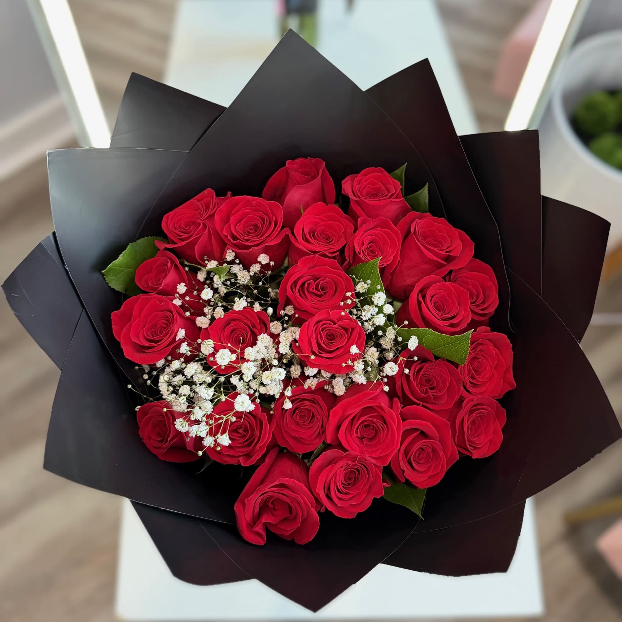Bouquet of red roses with white baby's breath in black wrap