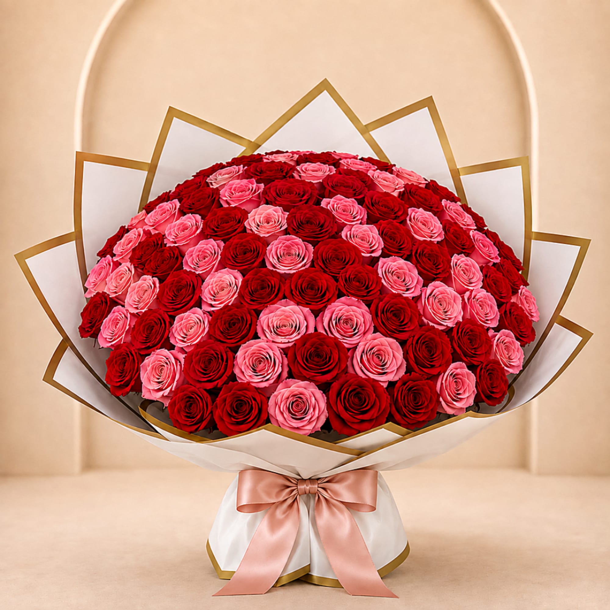 Large bouquet of red and pink roses wrapped in white paper with a satin ribbon
