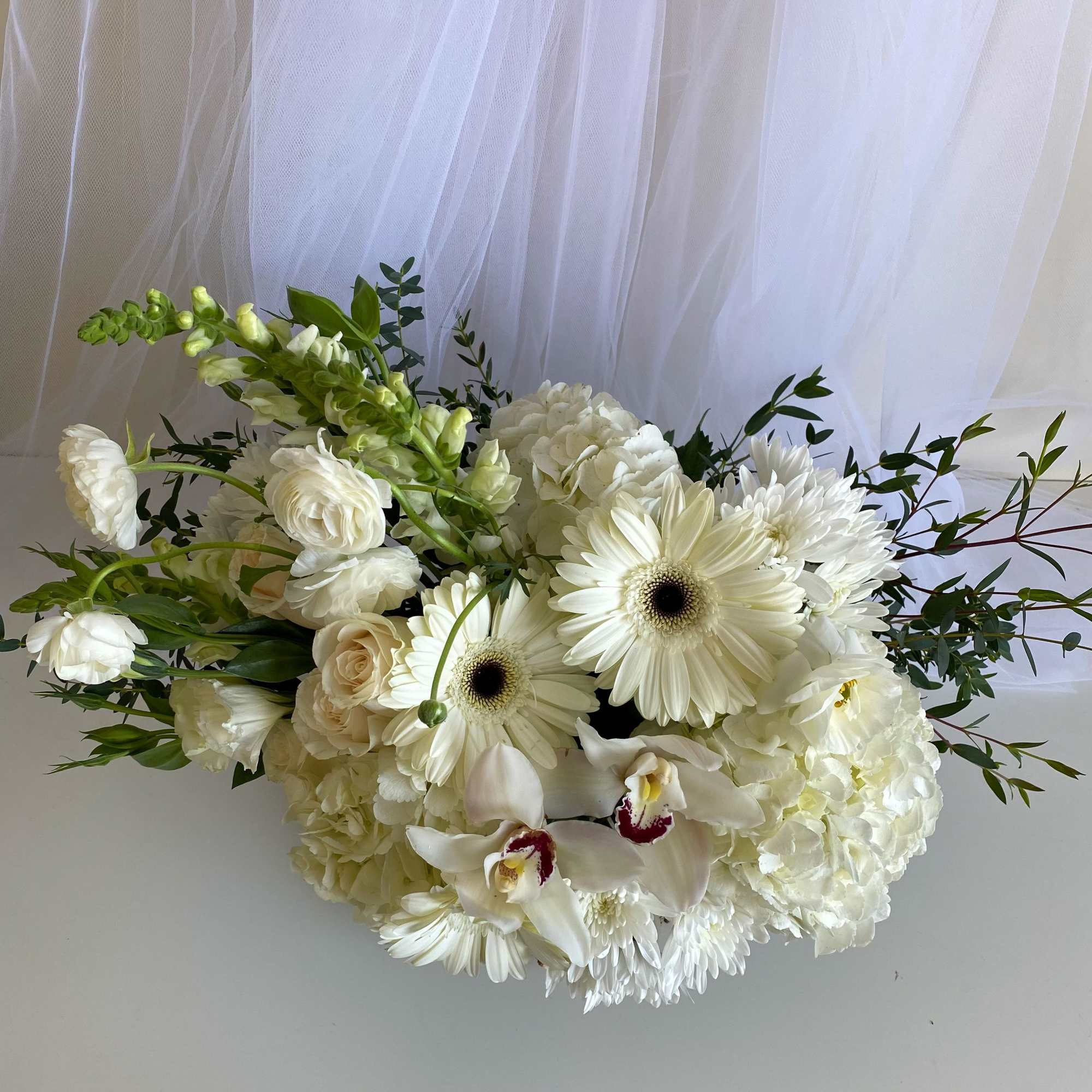 White floral bouquet with gerbera daisies, orchids, and hydrangeas