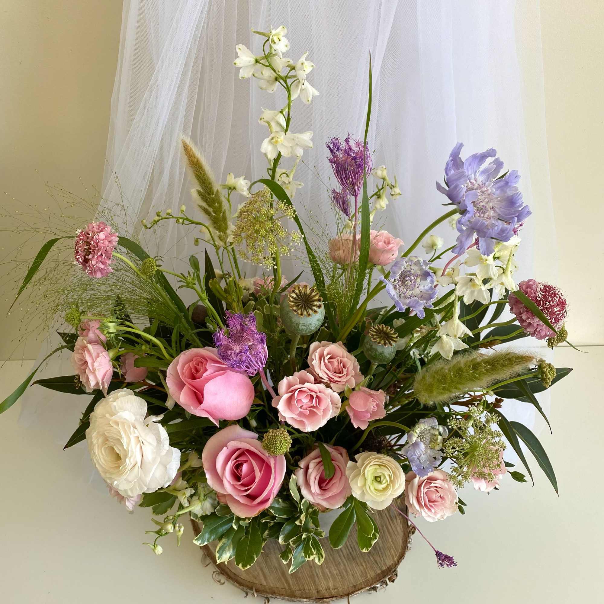 Mixed pink, white, and lavender flowers arranged in a rustic container