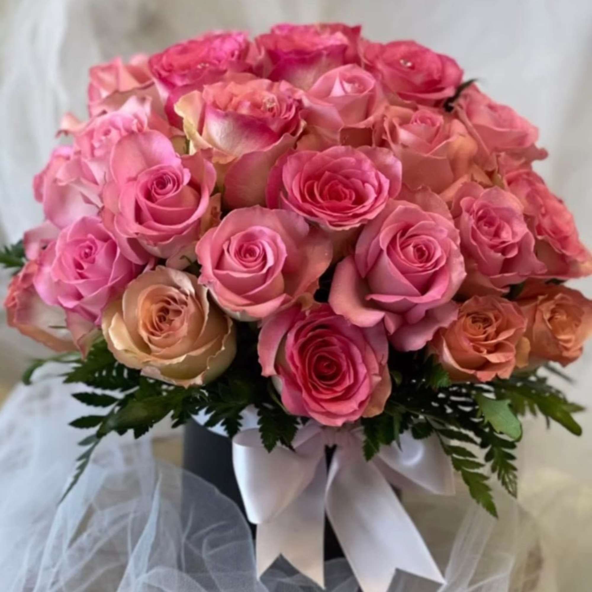 Bouquet of pink and peach roses with a white ribbon