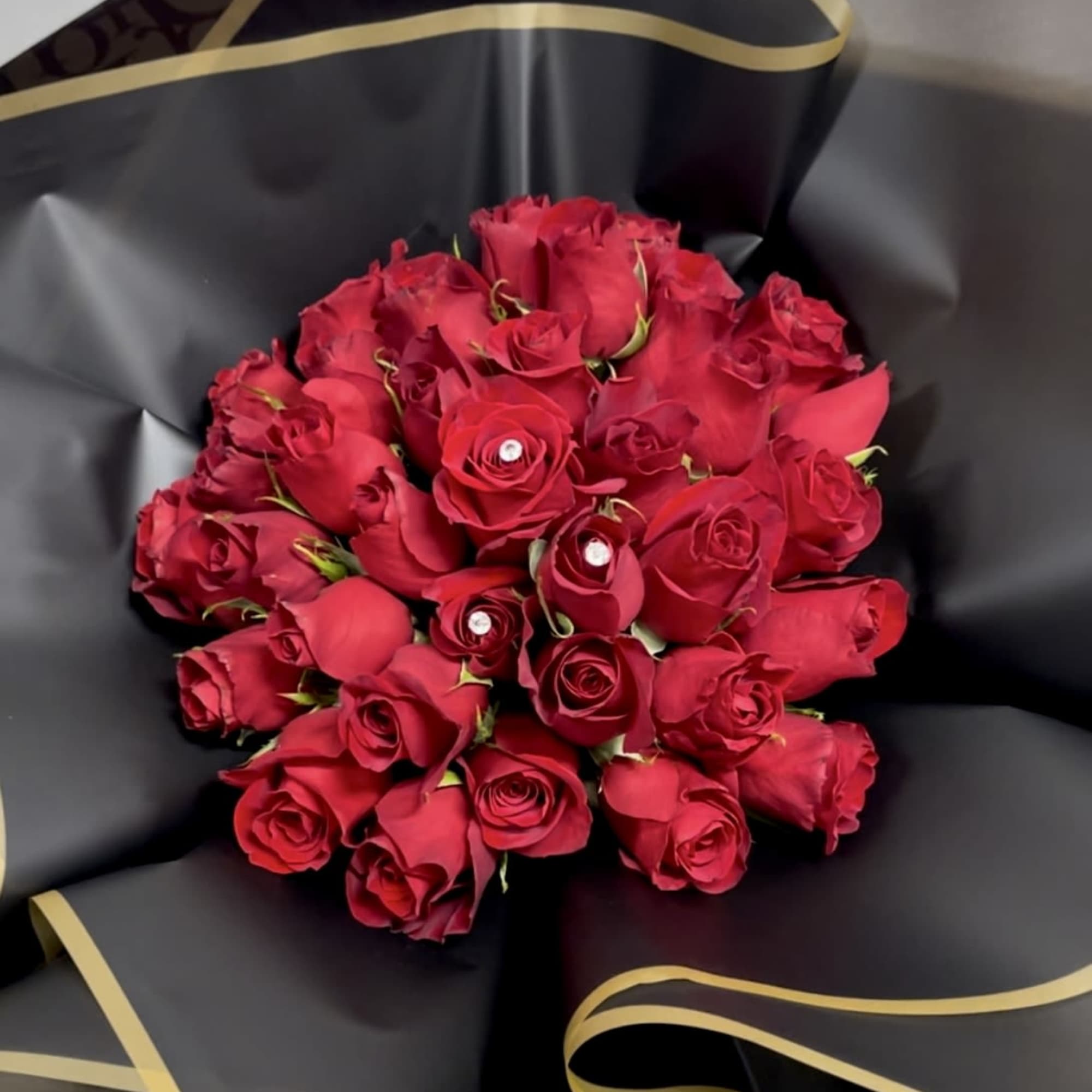 Bouquet of red roses wrapped in black paper with gold trim