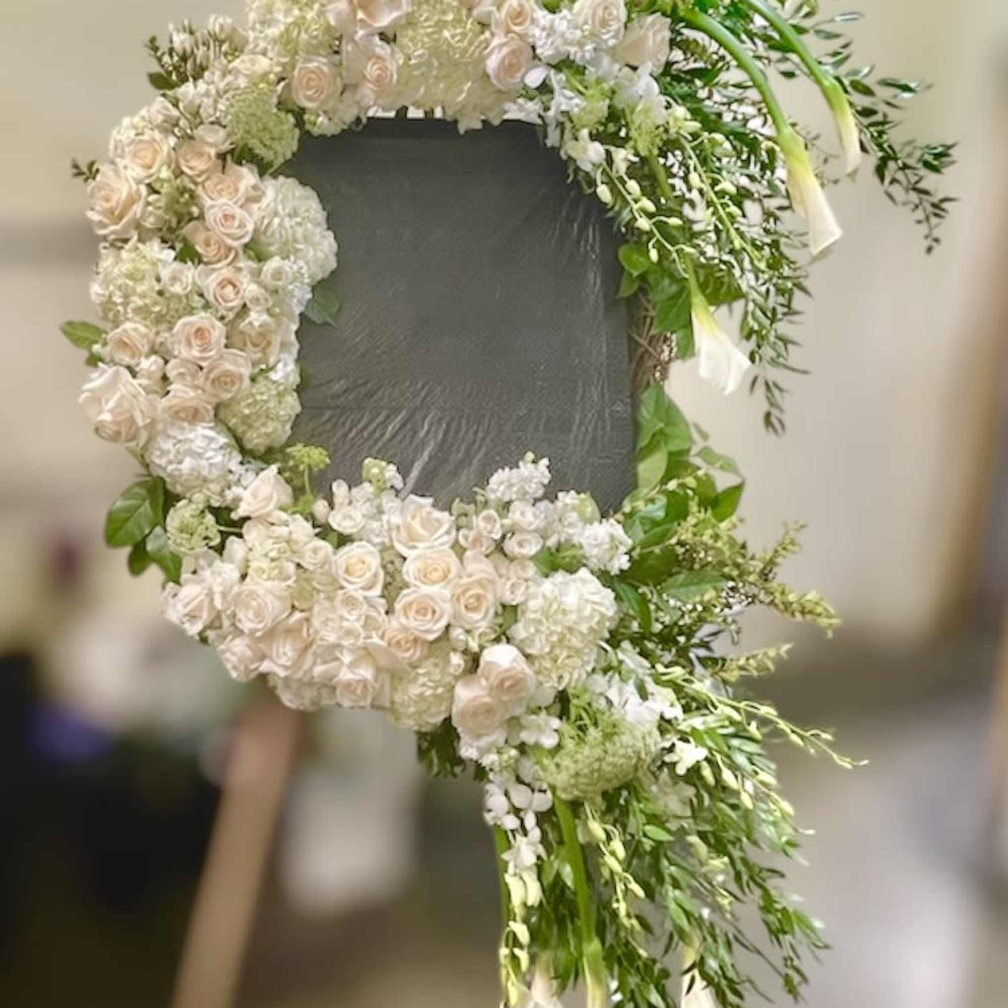 Large floral wreath of pale roses and white blooms on a stand
