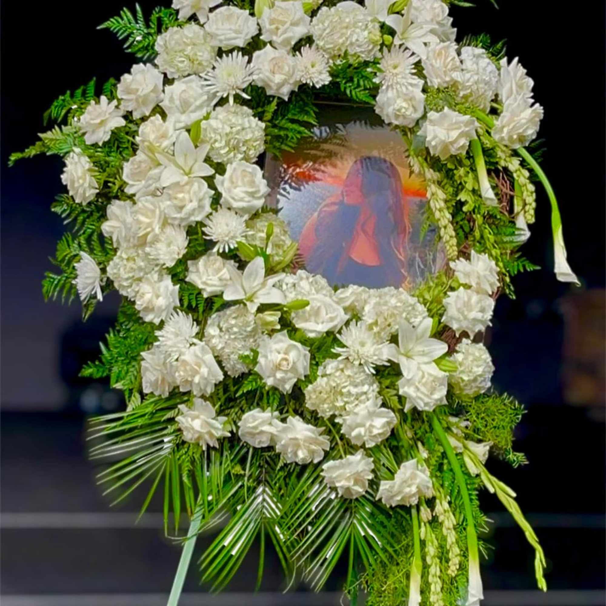 White floral funeral wreath with a photo in the center